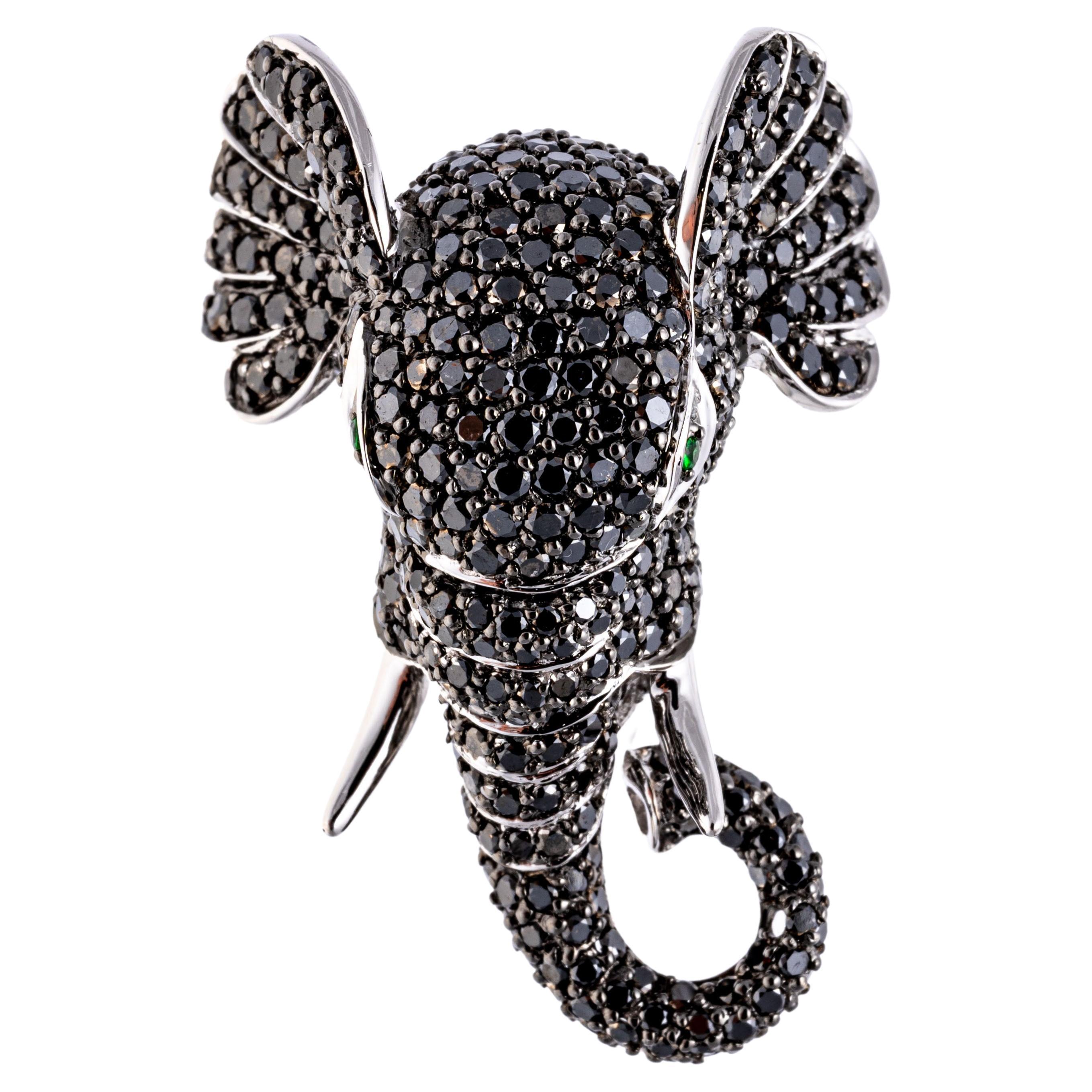 14k white gold ring. This handsome ring is a regal figural elephant head,  trimmed in the entirety with pave set, round faceted black diamonds, approximately 2.01 TCW.  Round faceted, bright green tsavorite garnets, approximately 0.04 TCW, set as