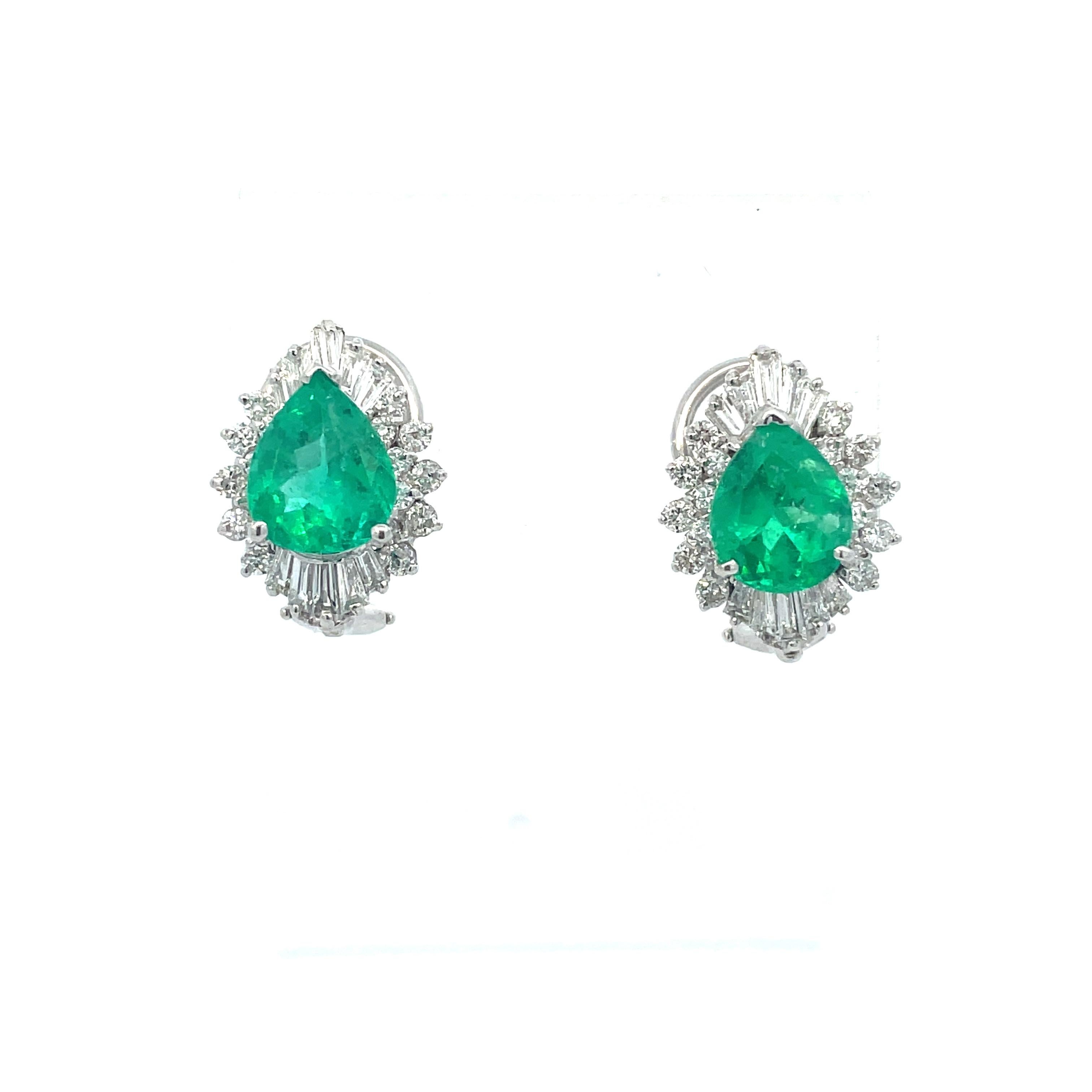 This is an impressive pair of outstanding pear-shaped Emerald earrings crafted in 14K white gold and surrounded by a sparkling burst of baguette and round diamonds. The breathtaking stones in these exquisite earrings--together weighing in at an