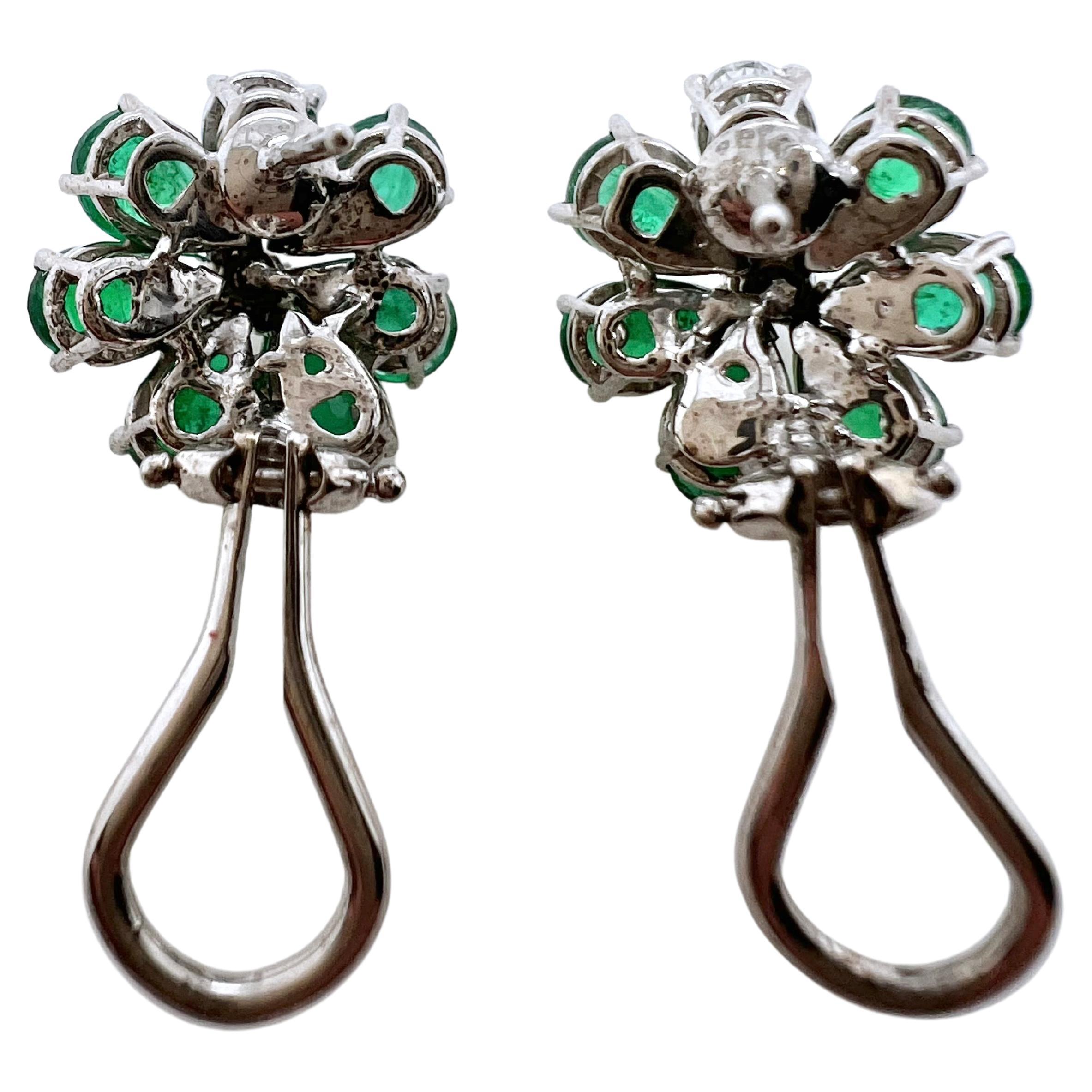 This unusual pair of emerald and diamond earrings are breathtaking!  The pear shaped emeralds are arrange
surrounding the round brilliant and pear shaped diamond to give a dramatic look.  The lush, vibrant green in the
emeralds contrast the white,