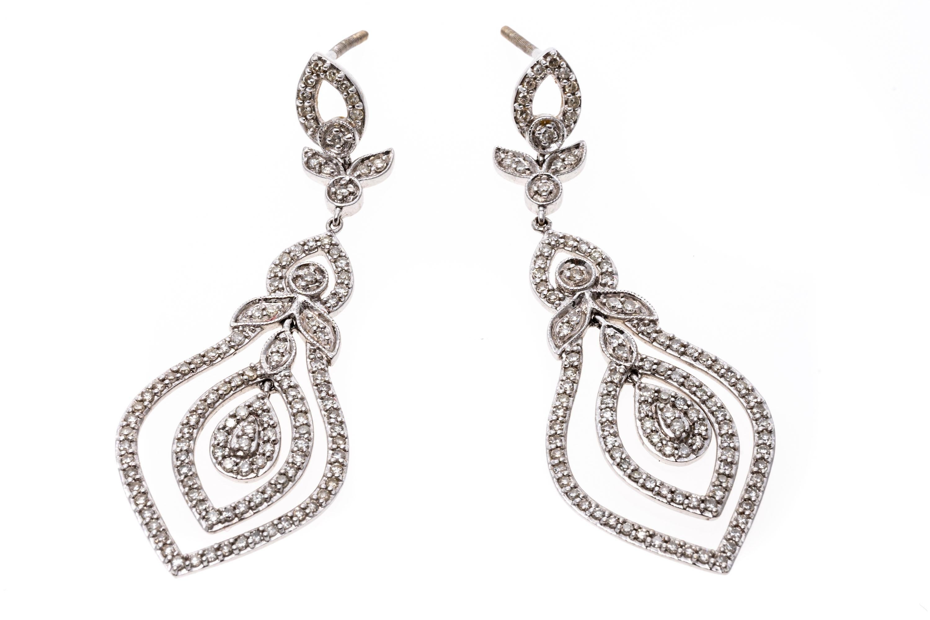 Elegant and elaborate, this pair of 14K white gold pendant style earrings is set with dazzling diamonds. Suspended from the base of the earrings is a nested series of rings that move and shimmer as the wearer moves. Diamonds are approximately 1.5