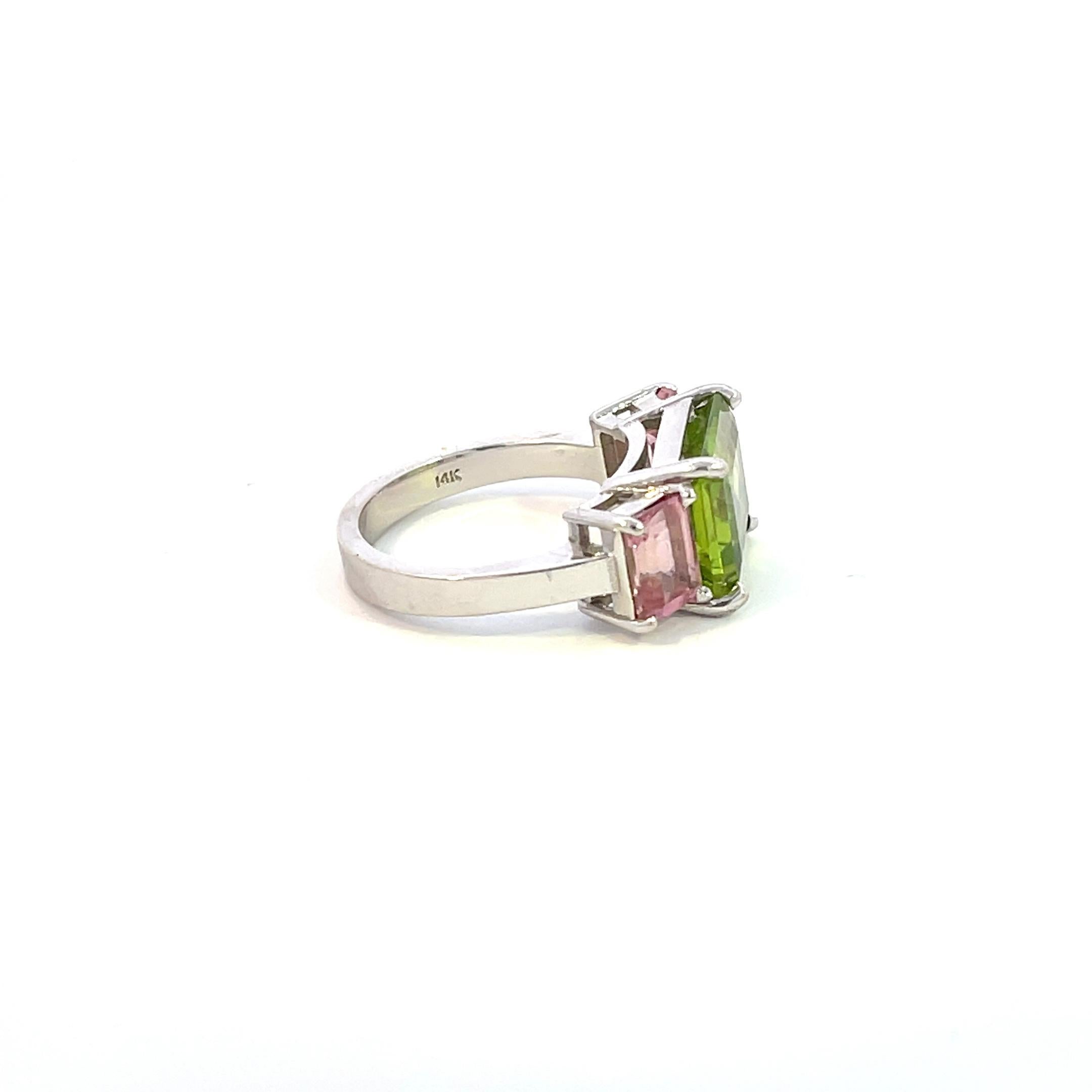 This is a one-of-a-king ring that you won''t want to miss out on! 

The center stone is an Emerald Cut Green Peridot Stone weighing approx 5.25cts (11.20 x 9.20mm) and is paired with Two (2) Emerald Cut Pink Sapphires weighing approx 1ct each stone