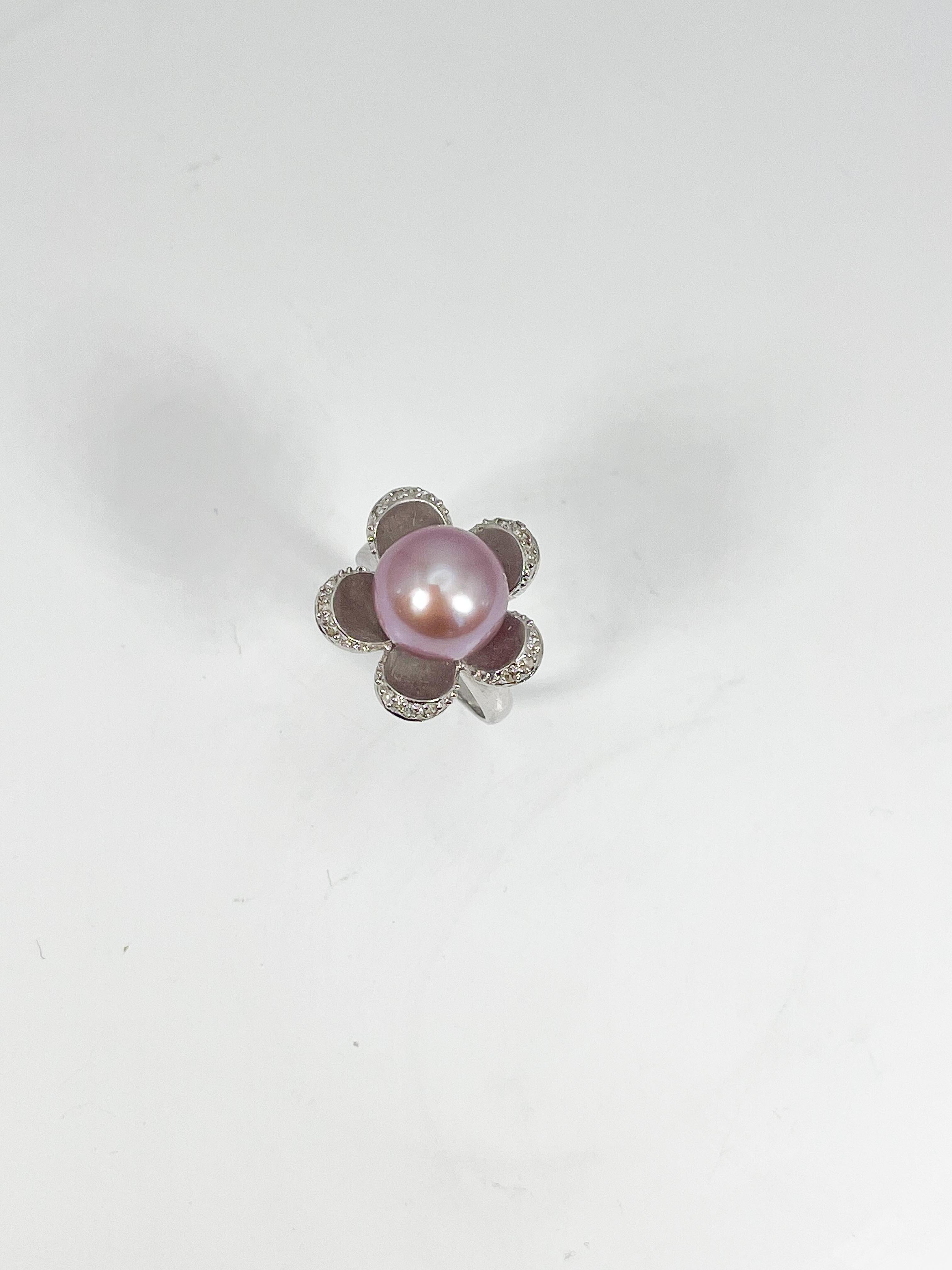 14k white gold pink cultured pearl and diamond flower ring. The diameter of the pearl is 10.8 mm, all diamonds in this ring are round, the ring size is 6 1/2, and it has a weight of 6.17 grams.