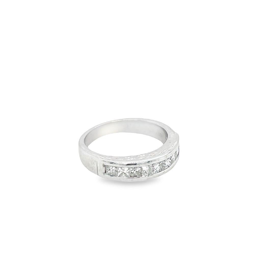A wedding band made of 14K white gold. It features nine (9) princess cut diamonds weighing a total of 1.00 carat. The diamonds are set in a channel on the front half of the ring, adding a modern and dazzling touch. The diamonds are G-H color and
