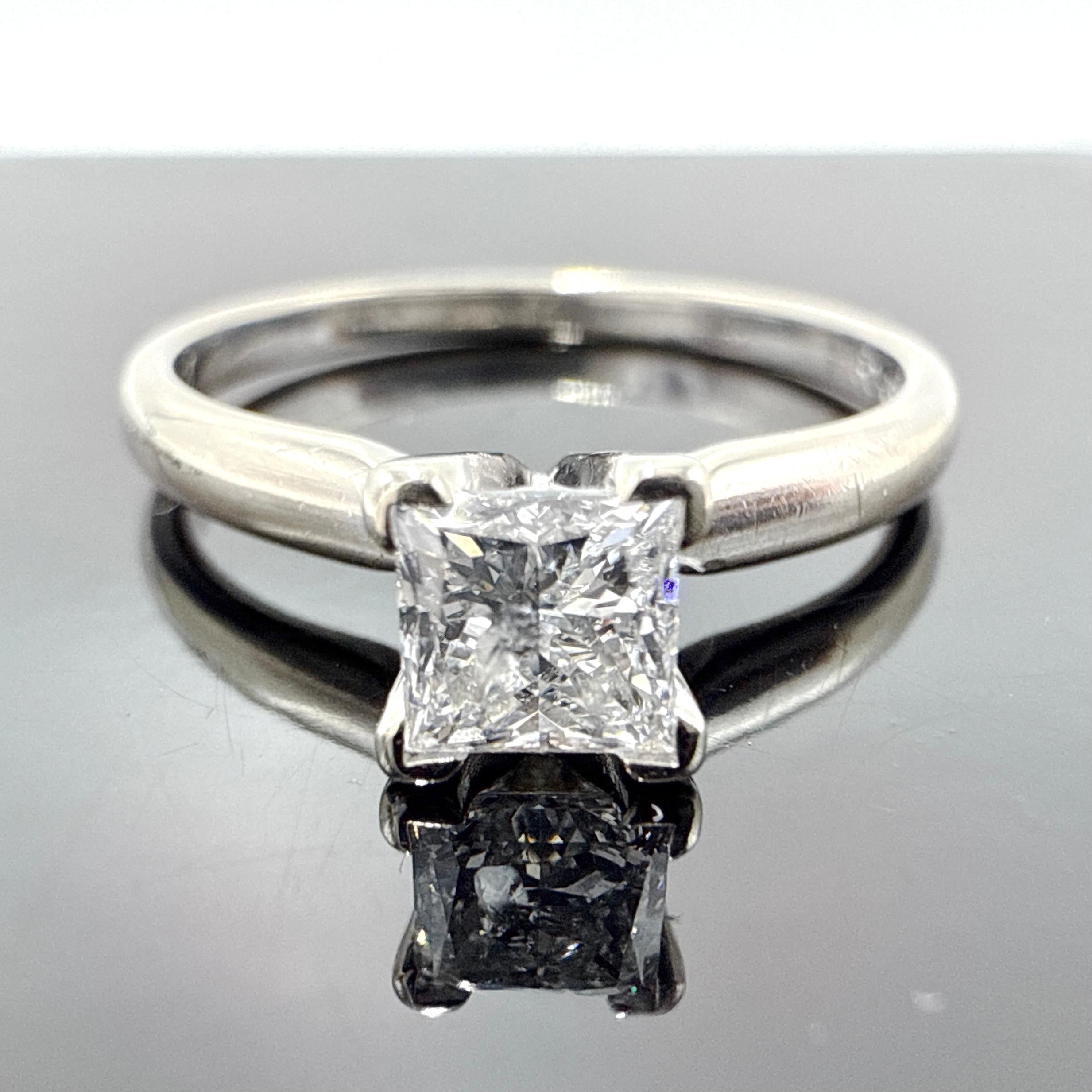 Il s'agit d'une bague de fiançailles en or blanc 14 carats sertie d'un diamant de taille princesse de 0,56 carat. La bague est coulée à la cire, assemblée à la main et finie avec un haut degré de polissage. Le diamant est serti entre des épaules