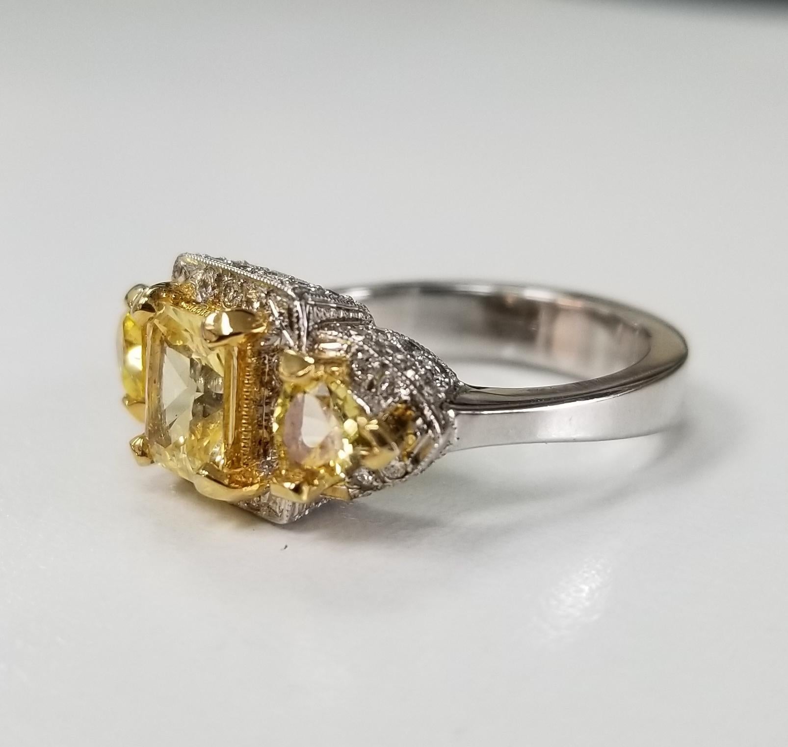 14k white gold yellow sapphire halo and diamond ring, containing 1 radiant cut weighing 1.22cts. , 2 trillion cut yellow sapphires weighing .74pts. all of very fine quality and 58 round full cut diamonds of very fine quality weighing .55pts.  This