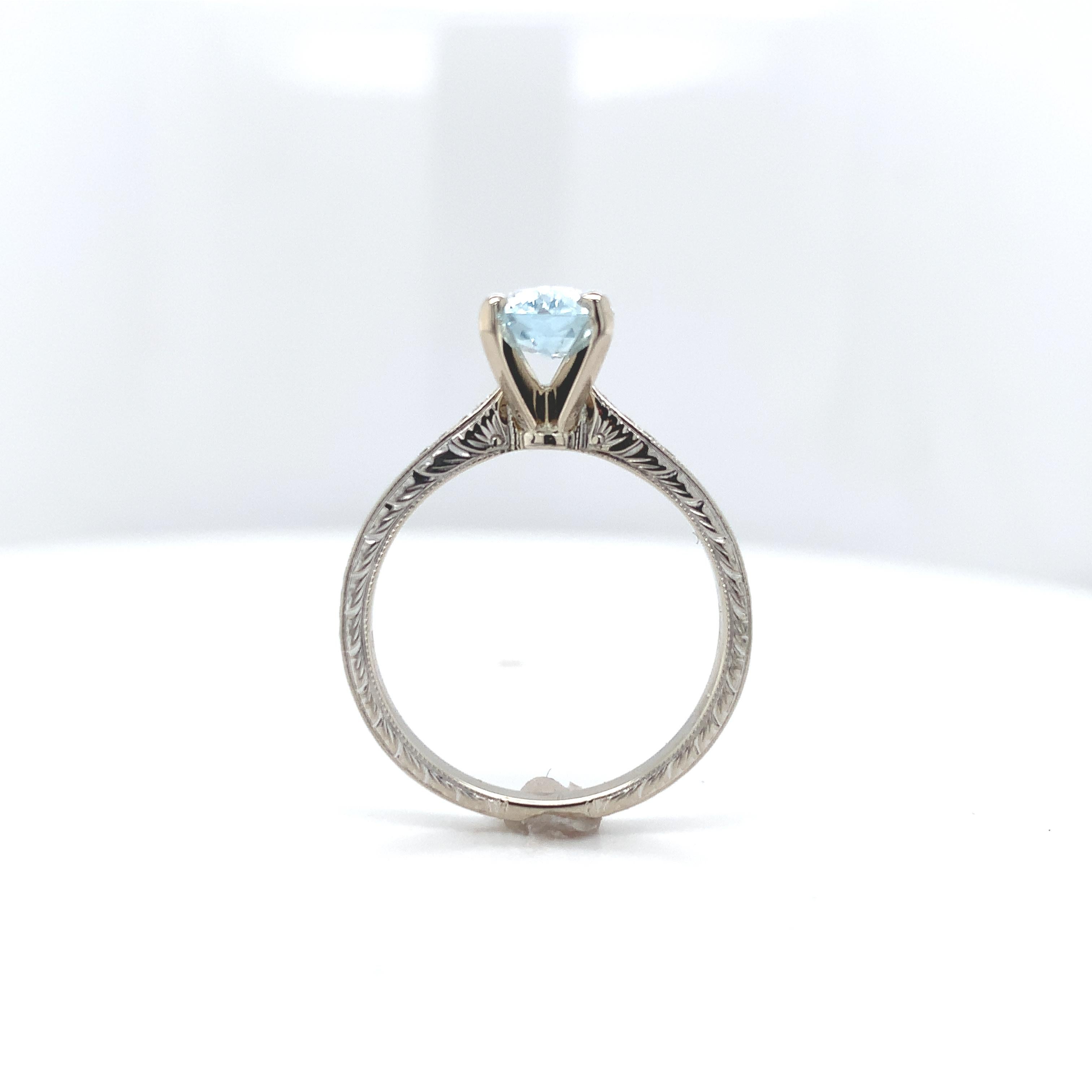 14K white gold aquamarine and diamond ring featuring a specialty cut aquamarine weighing 1.18 carats. The aquamarine measures about 9mm x 6.5mm. It is an elongated hexagon with light blue color. The aquamarine is set in a high solitaire head in a