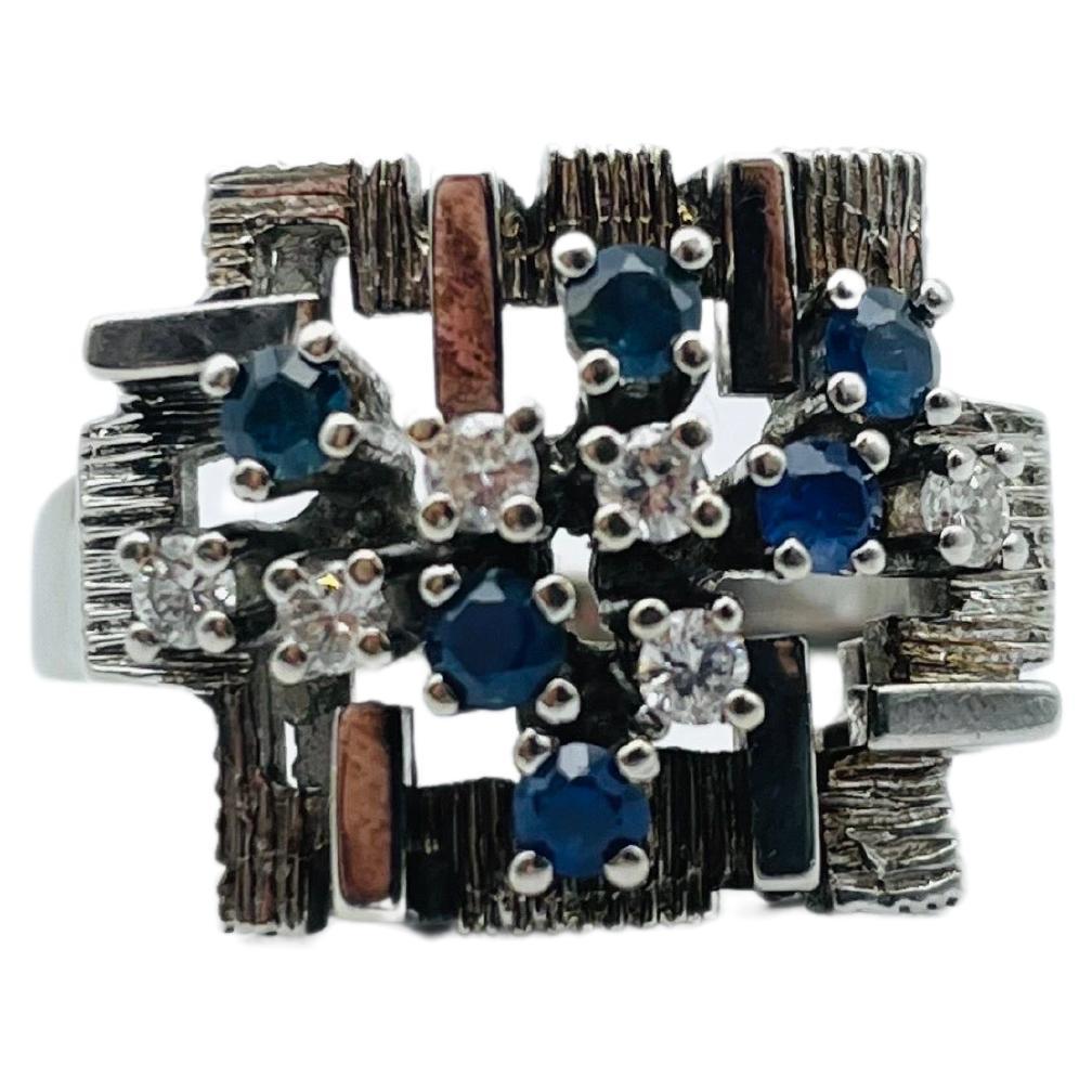 Introducing the epitome of glamour and sophistication, the 14k white gold cluster ring with brilliants and sapphire. This exquisite piece of jewelry boasts a solid band crafted from 14 karat white gold, which serves as a pristine canvas for the