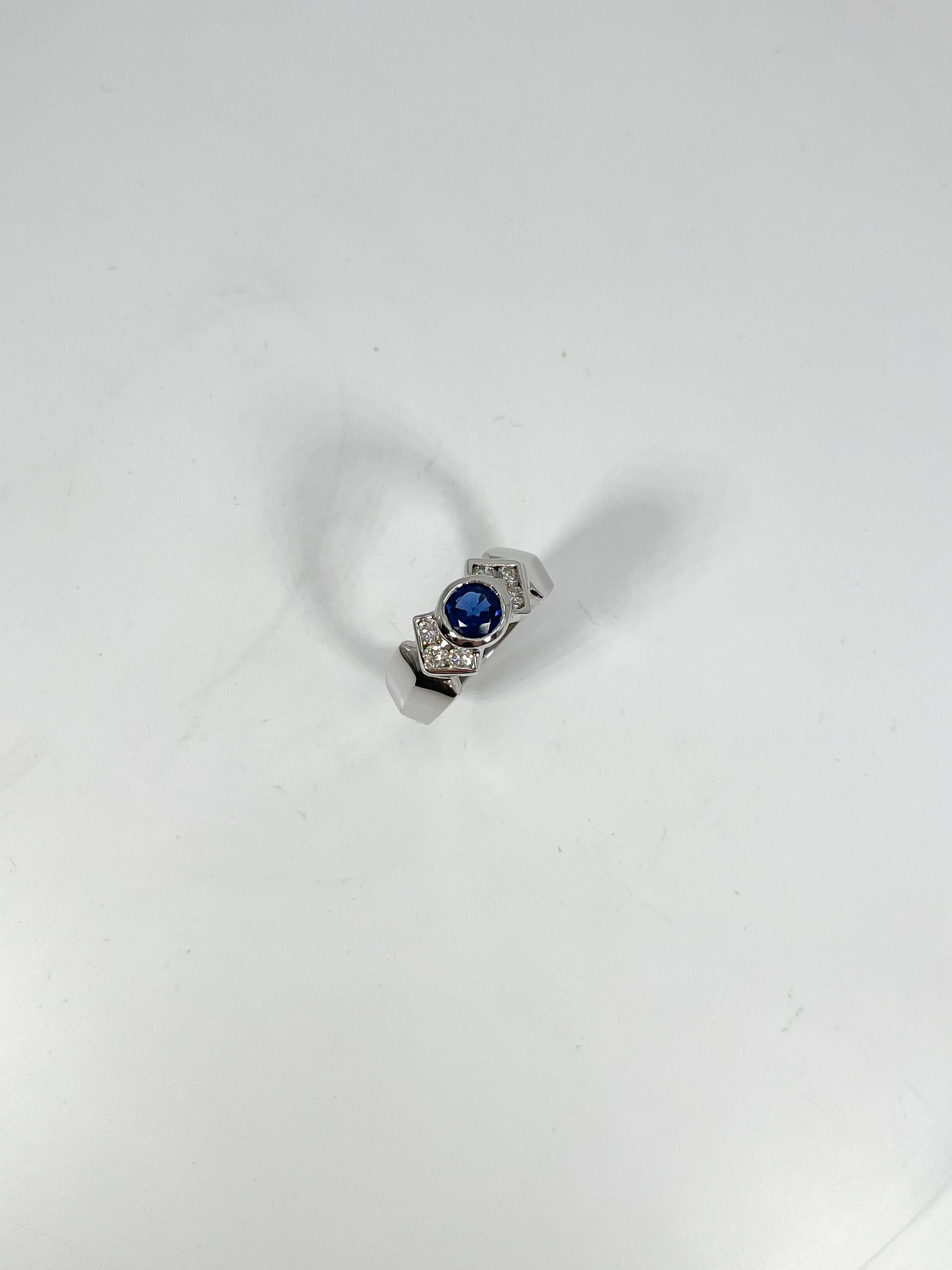 14k white gold round bezel .60 CT sapphire and .50 CTW diamond ring. the stones in this ring are all round, three diamonds on both sides of sapphire, the width is 7.8 mm. the stone diameter measures 7.1 mm, size 6 1/4, and it has a total weight of