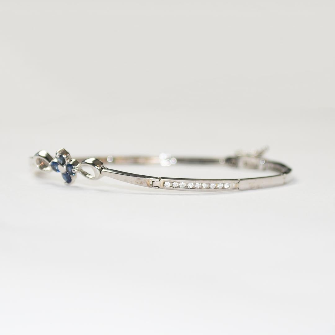 Bracelet en or blanc 14k avec diamants et saphir.
Marqué 14k et pèse 6,9 grammes.
Il y a quatre saphirs bleus naturels au sommet du bracelet, .30 carats au total, et une bonne couleur.
Il y a 18 petits diamants ronds de taille brillant sur les