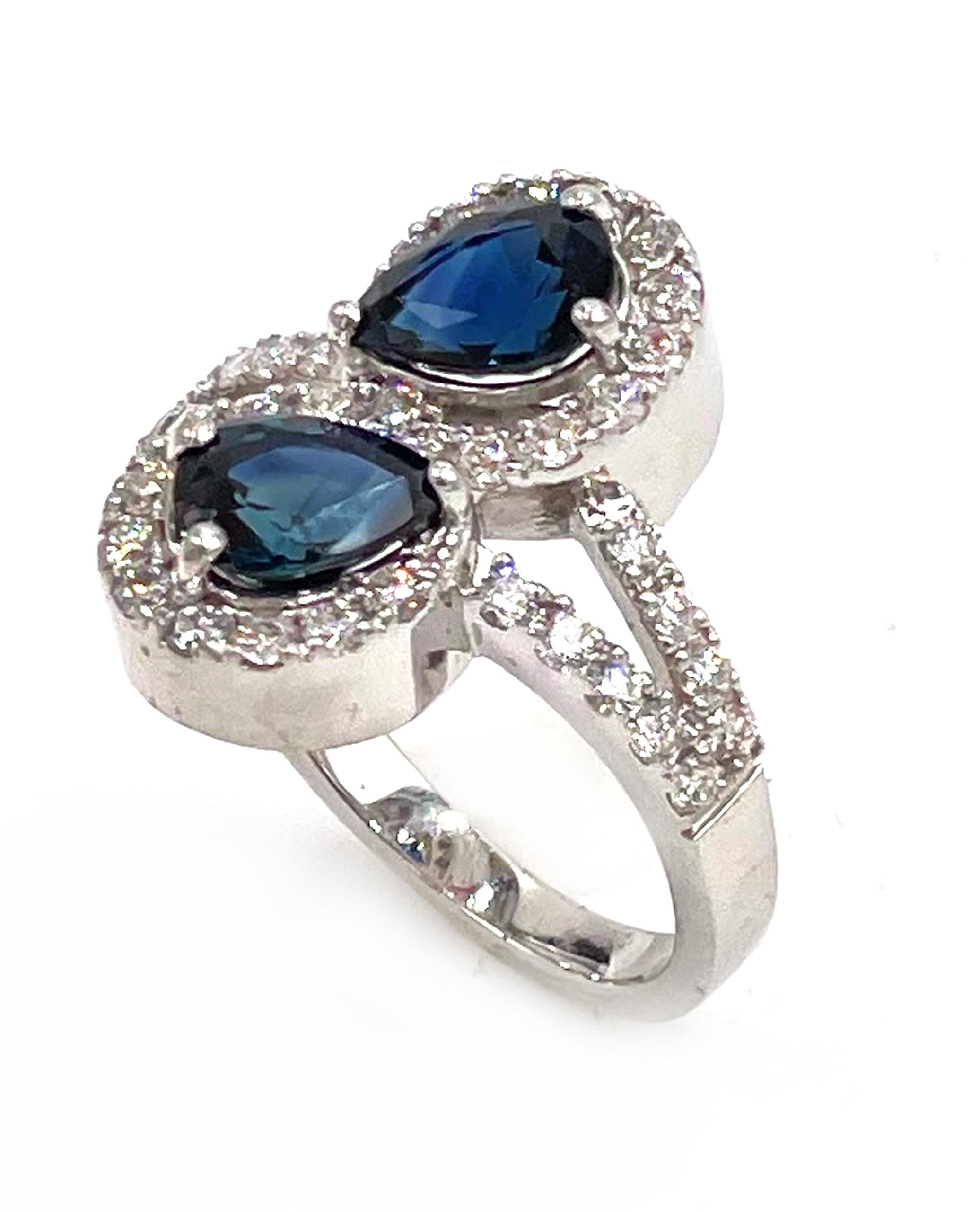 14K white gold split shank bypass ring featuring two pear shape blue sapphires 1.96 carats total weight.  The sapphires are haloed with round brilliant-cut diamonds. There are total of 40 round brilliant-cut diamonds weighing 0.65 carats.

*