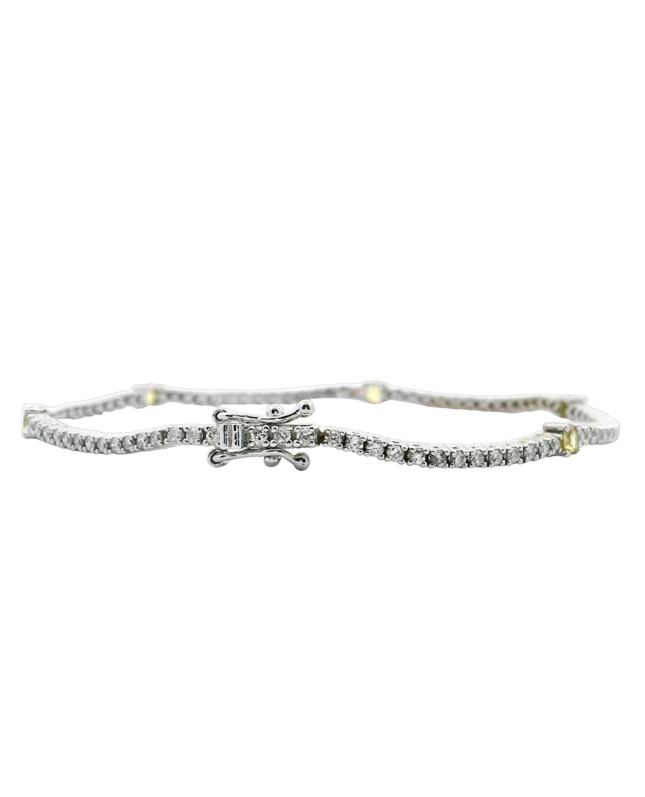 14K white gold tennis bracelet with 87 round brilliant-cut diamonds weighing 1.50 carats total and 5 round faceted yellow sapphires weighing 0.70 carats total.

- The bracelet is 7 inches long and has two figure eight safety clasps.