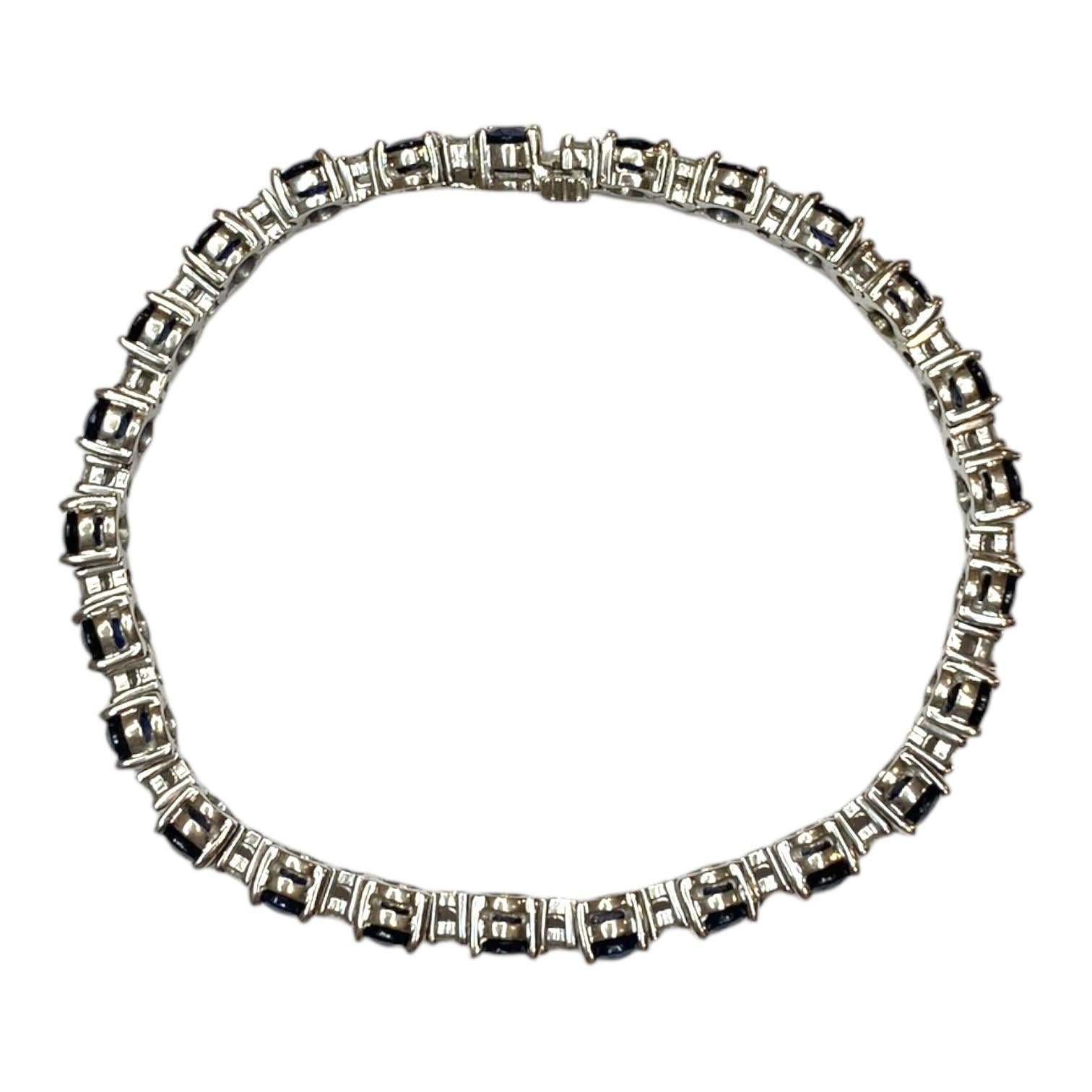 Dieses aus 14 Karat Weißgold gefertigte  Das Tennisarmband besteht aus einer Reihe von fünfundzwanzig blauen Saphiren im Ovalschliff mit einem Gesamtgewicht von 14,0 Karat. Jeder Saphir ist mit weißen Diamanten im Brillantschliff mit einem Gewicht