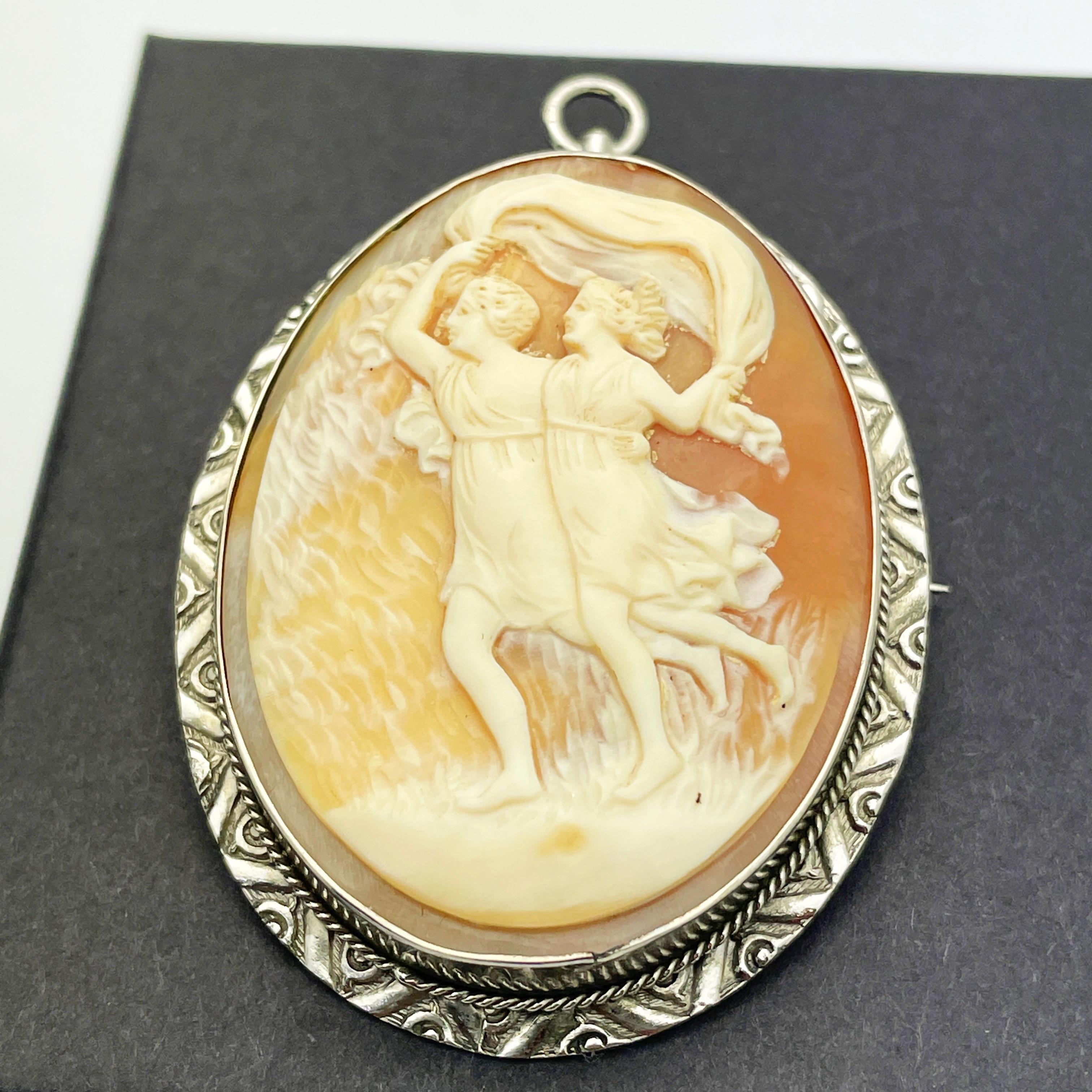 Here is a lovely 14k White Gold Shell Cameo Pendant/Brooch.

This brooch features an oval shaped reddish brown shell cameo featuring a woman and man running with a veil. Shell measures approx. 38.25mmx 30.00mm. Can be worn either as a brooch or a