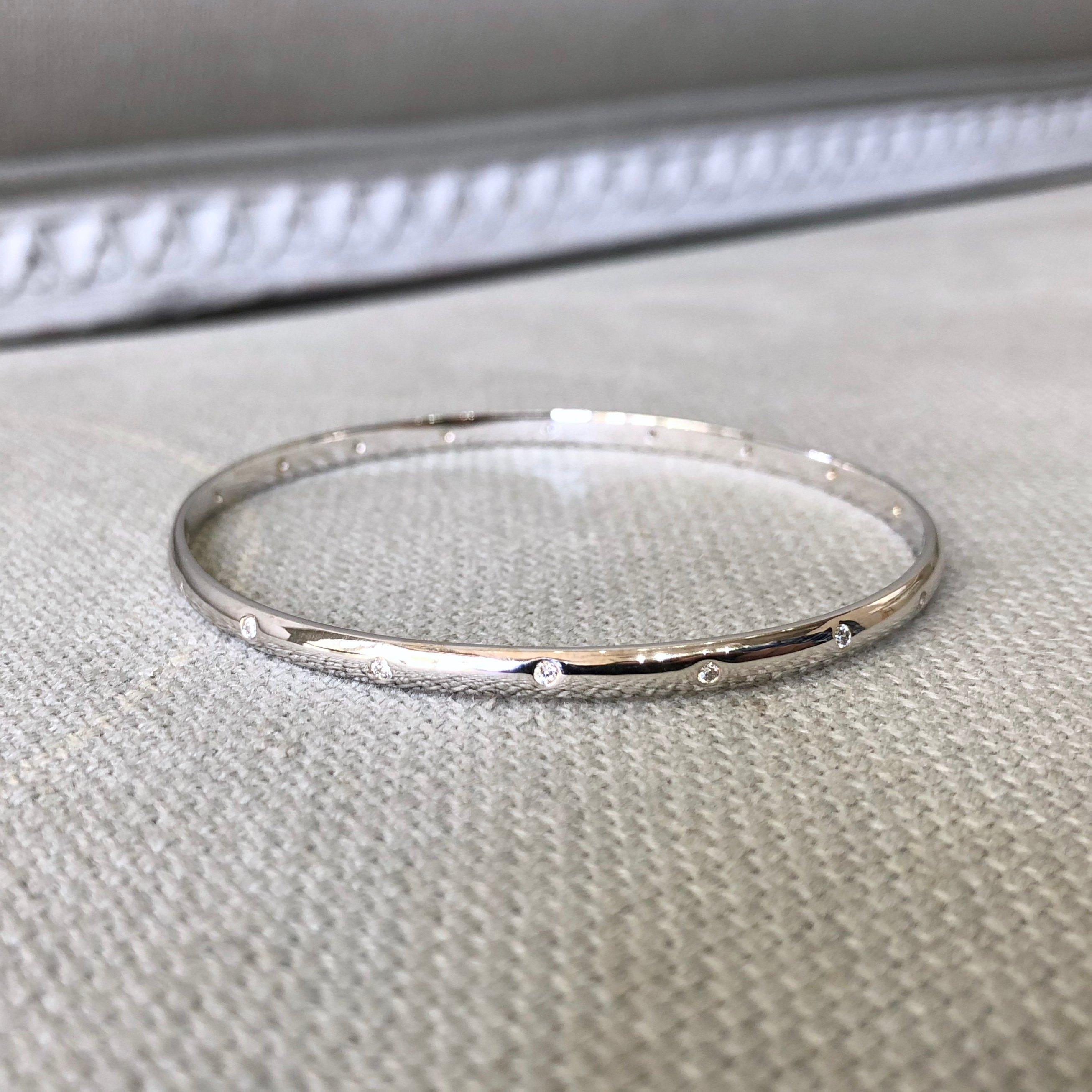 A ladies 14k white gold round bangle contains eighteen (18) burnish set Round Brilliant Cut Diamonds that measure 1.7mm x 1.7mm and weigh a total of 0.36 carats with Color Grade G and Clarity Grade VS-SI. The bangle weighs 12.5 grams (8 pennyweight)