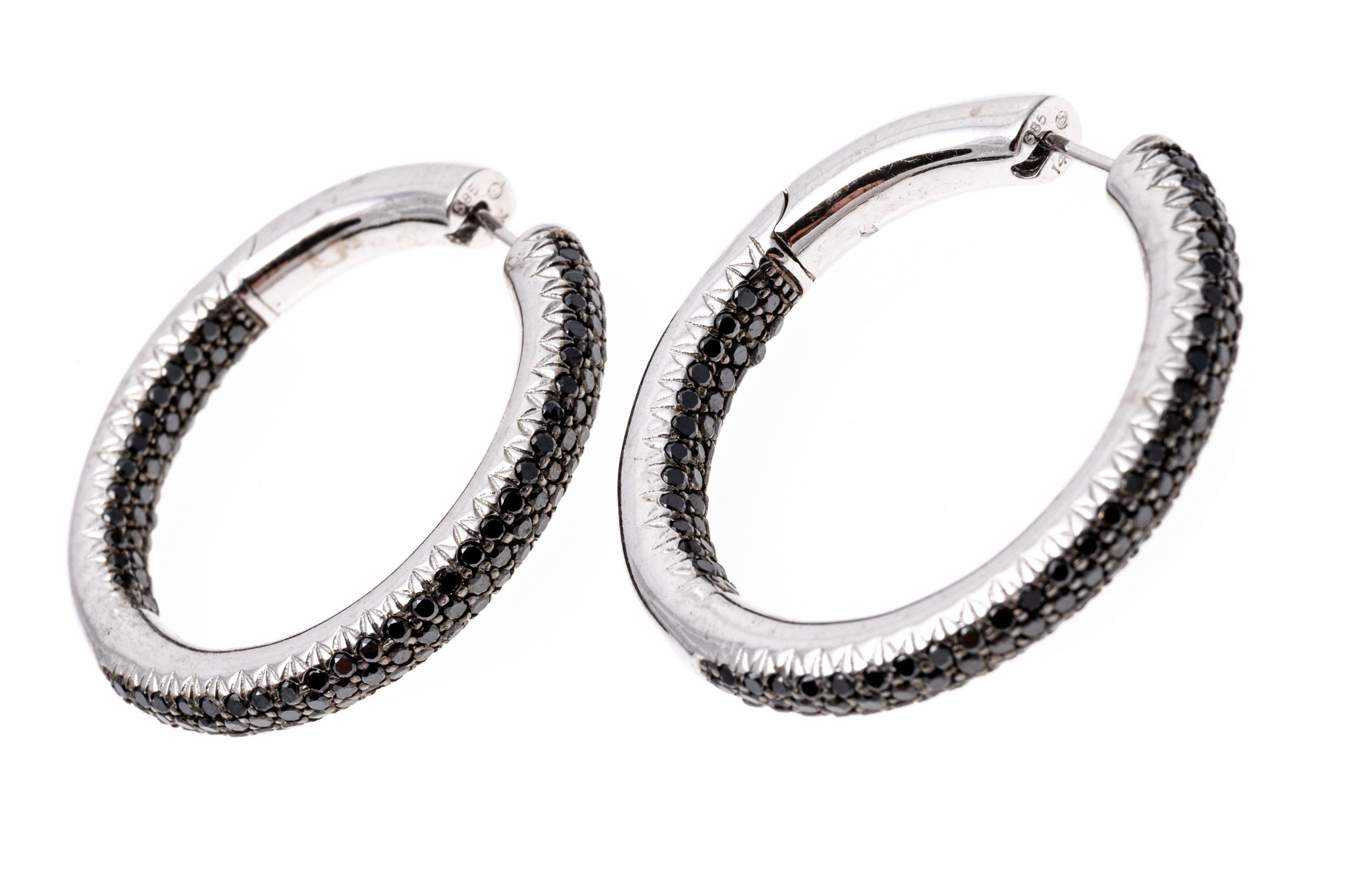 14k white gold earrings. These stunning hoop earrings are a rounded tube style, pave set with round faceted black diamonds, 2.85 TCW. The earrings have a post with a hinged, snap style back.
Marks: 14/585
Dimensions: 1