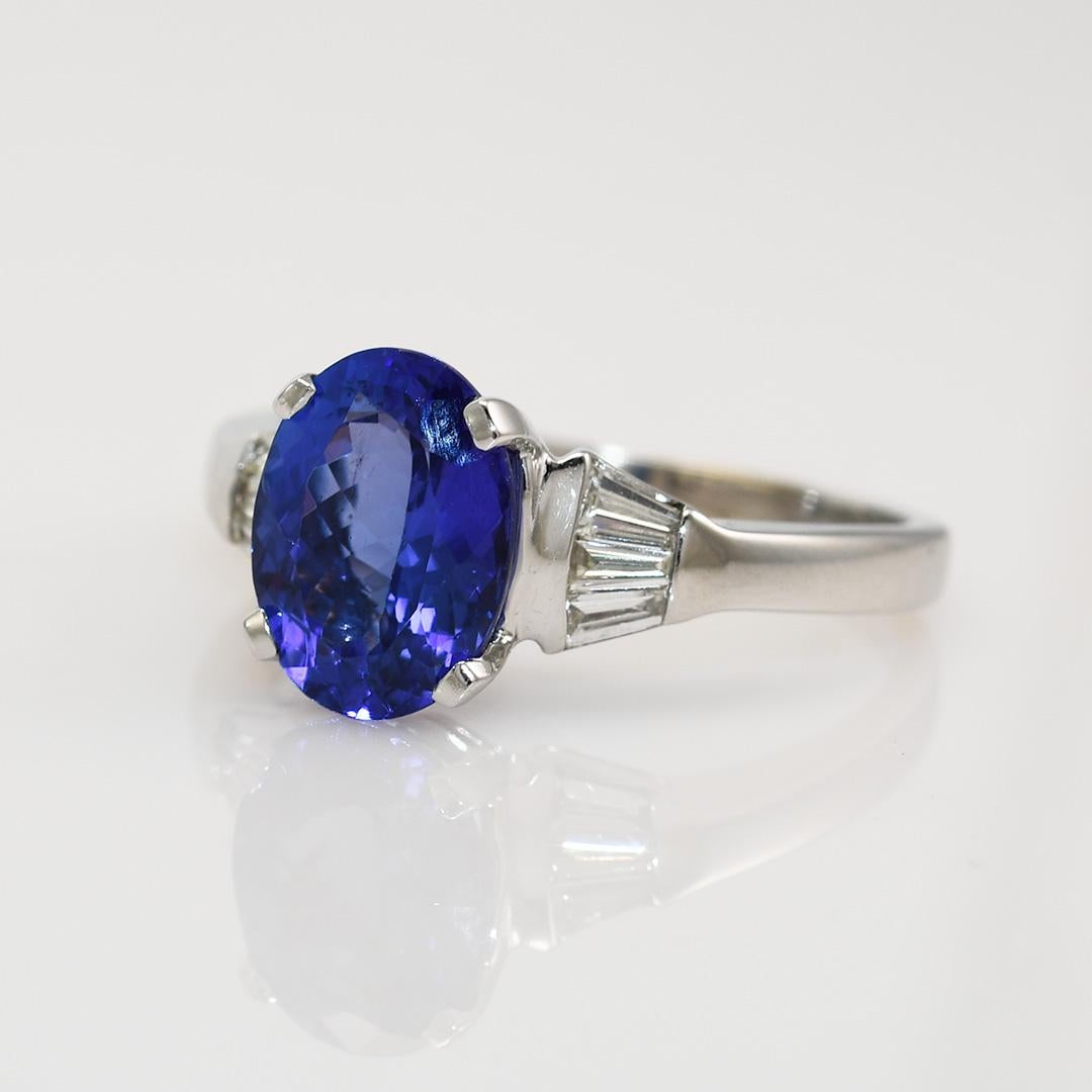 Ladies tanzanite and diamond ring with 14k white gold setting.

Stamped 14k and weighs 4.9 grams gross weight.

The oval shape tanzanite is a bluish-violet color with fancy faceting on the bottom, 3.00 carats.

There are six baguettes diamonds, .30