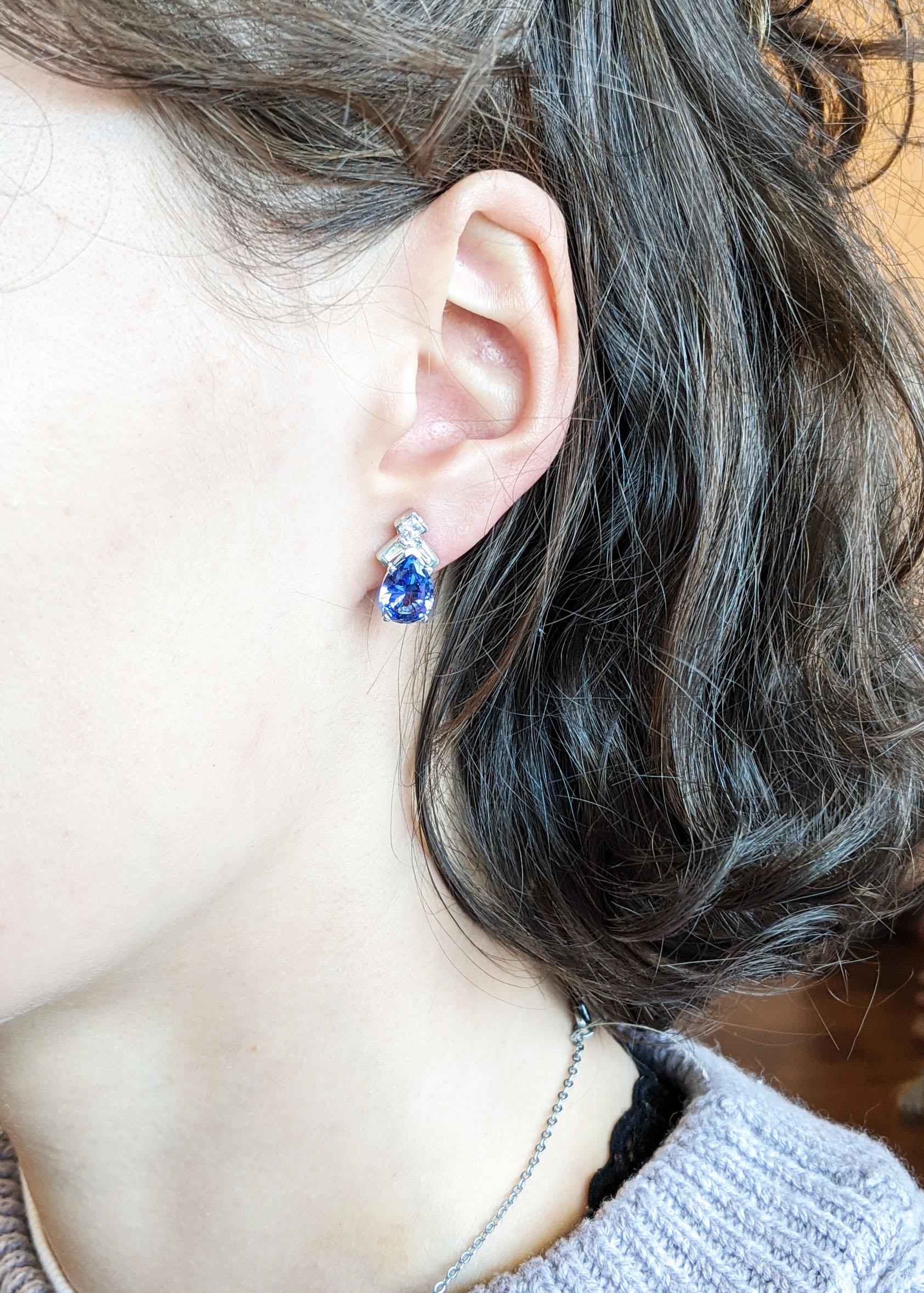 This is a gorgeous pair of stud earrings in 14k white gold with breathtaking pear-shaped purple and blue tanzanite centers. Each earring is accented with a square-cut diamond and two baguette diamonds that provide the perfect amount of sparkle to