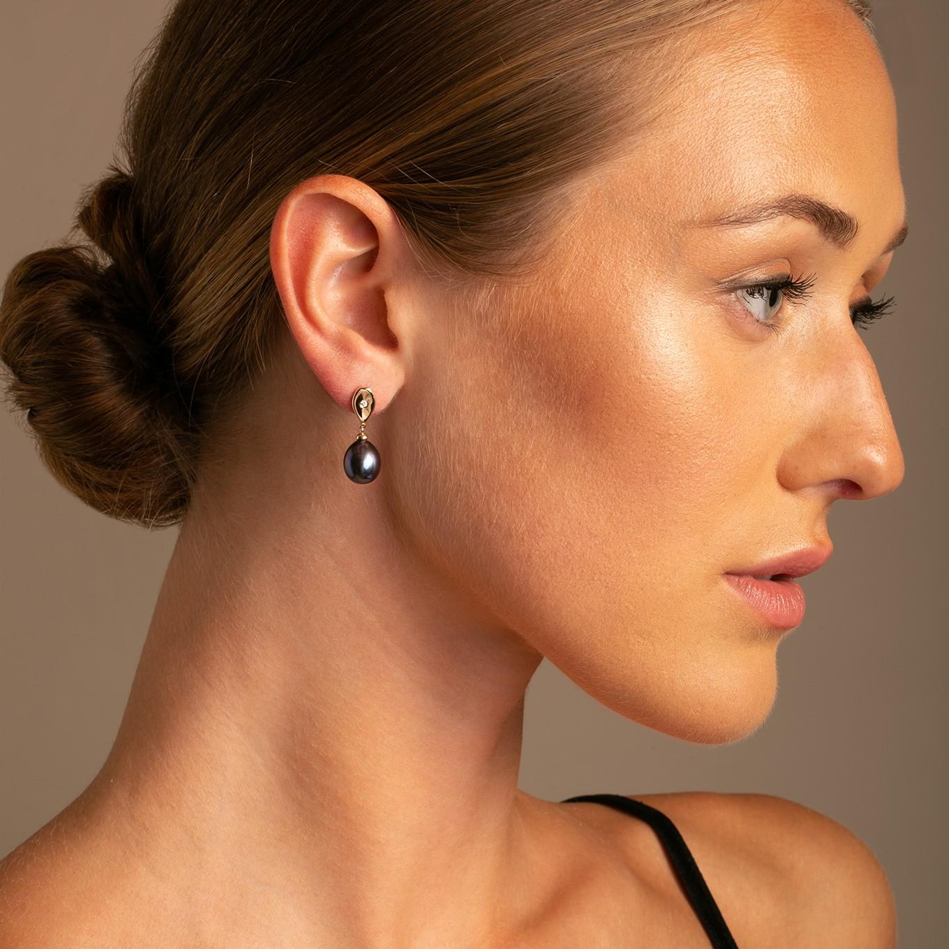 Die Teardrop-Ohrringe aus 14 Karat Weißgold mit Diamanten und pfauengrünen Perlen sind eine Mischung aus modernem Stil und klassischem Charme.

Jeder Ohrring ist mit einem raffinierten Teardrop-Design aus 14 Karat Weißgold versehen, das durch einen