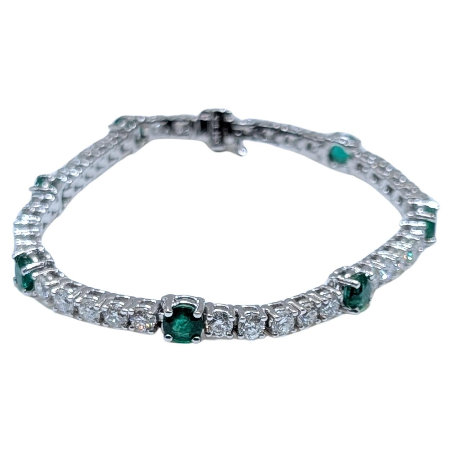 Dieses atemberaubende Tennisarmband aus 14 Karat Weißgold ist ein wahres Meisterwerk, das eine brillante Kombination aus runden Diamanten und leuchtenden Smaragden präsentiert. Das Armband ist mit 6,97 Karat sorgfältig gefassten runden Diamanten