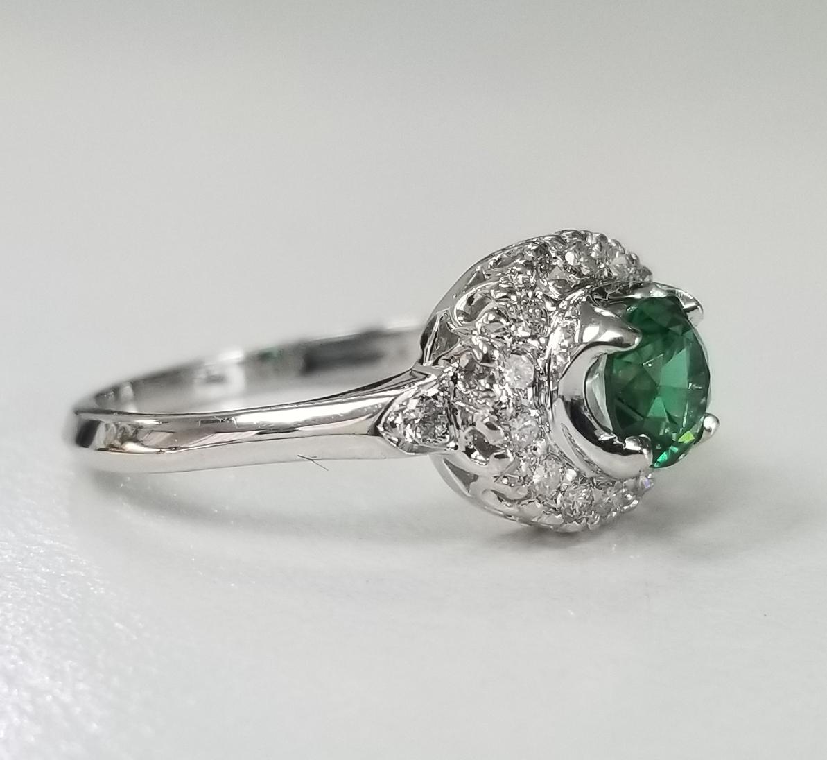 14k white gold tsavorite and diamond halo ring, containing 1 round cut  tsavorite weighing .50pts. and 16 round full cut diamonds of very fine quality weighing .25pts.  This ring is a size 5.5 but we will size to fit for free.

Tsavorite is a trade