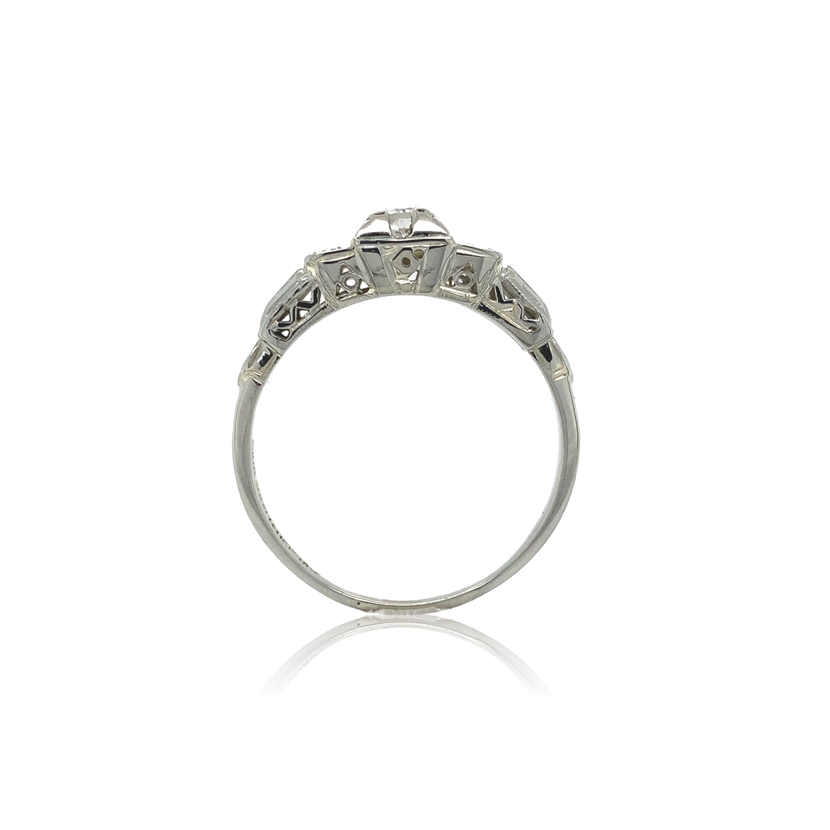 Vintage 14K white gold diamond ring. The round brilliant cut diamond measures about 3.6mm and weighs .19ct. The diamond has I2 clarity and H-I color. There are 4 small round accent diamonds weighing .08cts total. There is pierced filigree on the