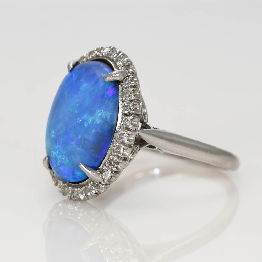 Ladies vintage opal and diamond ring in 14k white gold setting.
Stamped 14k and weighs 5.9 grams gross weight.
The Australian black opal measures 15.50 by 11mm.
Medium dome height.
  The opal has a black backing. No cracks in the opal.
The side