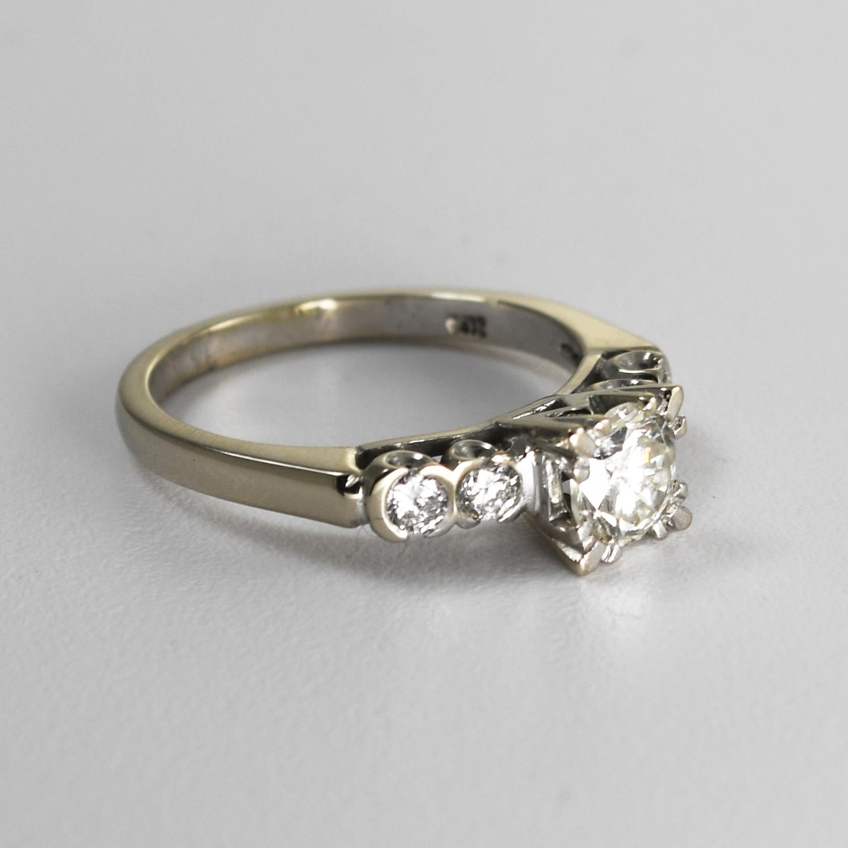 Anillo vintage de diamantes en oro blanco de 14k.
Lleva el sello de 14k y pesa 3,8 gramos.
El diamante central es una talla brillante redonda,  .75 quilates, color h,i, j, claridad SI.
Los diamantes laterales son brillantes redondos, color H,i, j,