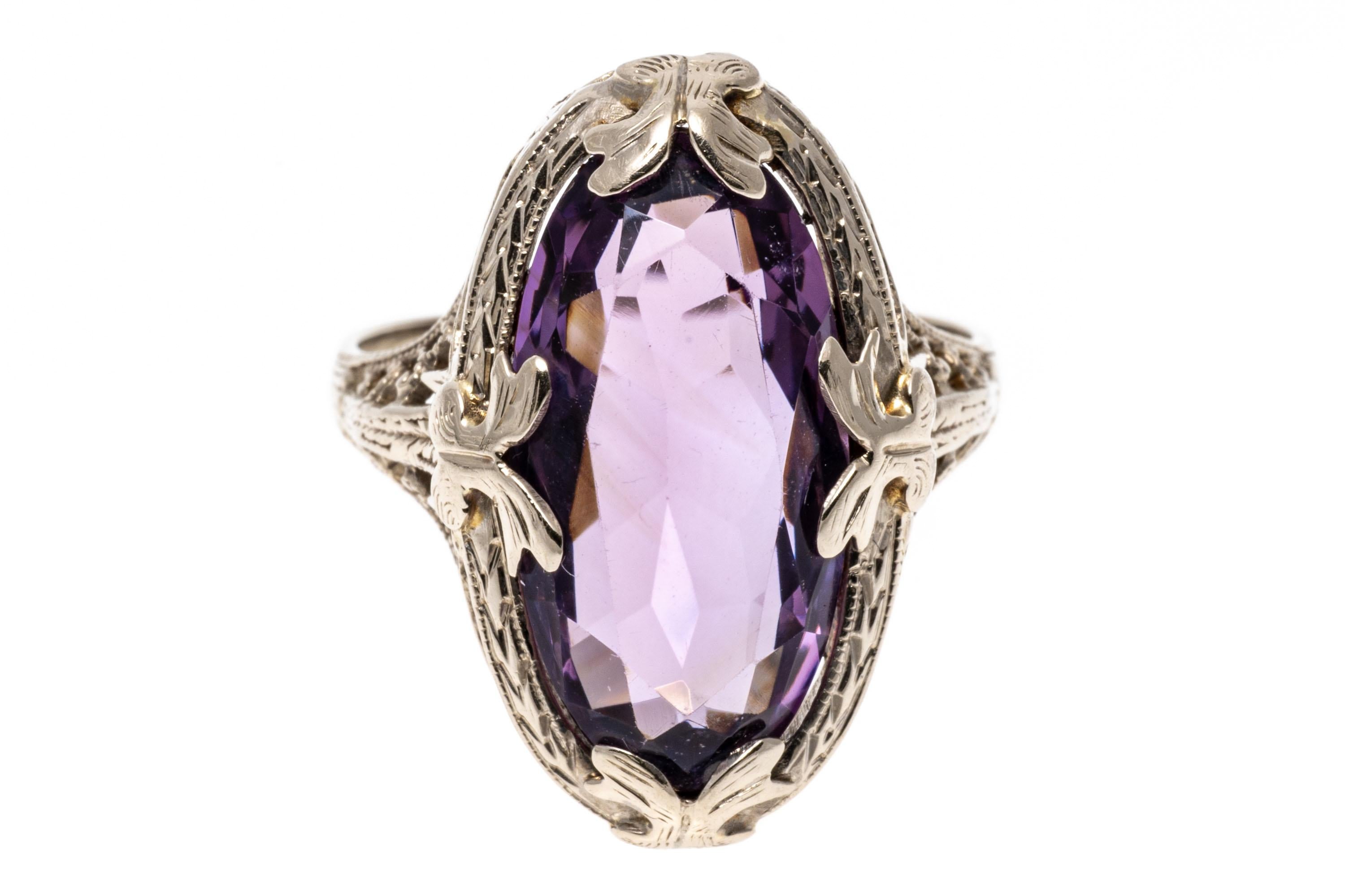 14k white gold ring. This pretty vintage ring is an elongated oval faceted, medium to light purple color amethyst, approximately 5.50 CTS and set with foliate prongs, with a filigree style gallery and shoulders.
Marks: 14k
Dimensions: 7/16