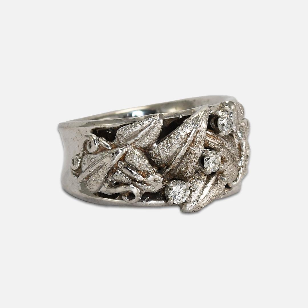 Anillo vintage femenino de oro blanco de 14k y diamantes.
Prueba un 56,5% de oro con un analizador XRF. 
El peso del anillo es de 10,6 gramos.
Los diamantes son de buena calidad, talla brillante redonda, 0,10 quilates en total.
La parte superior del