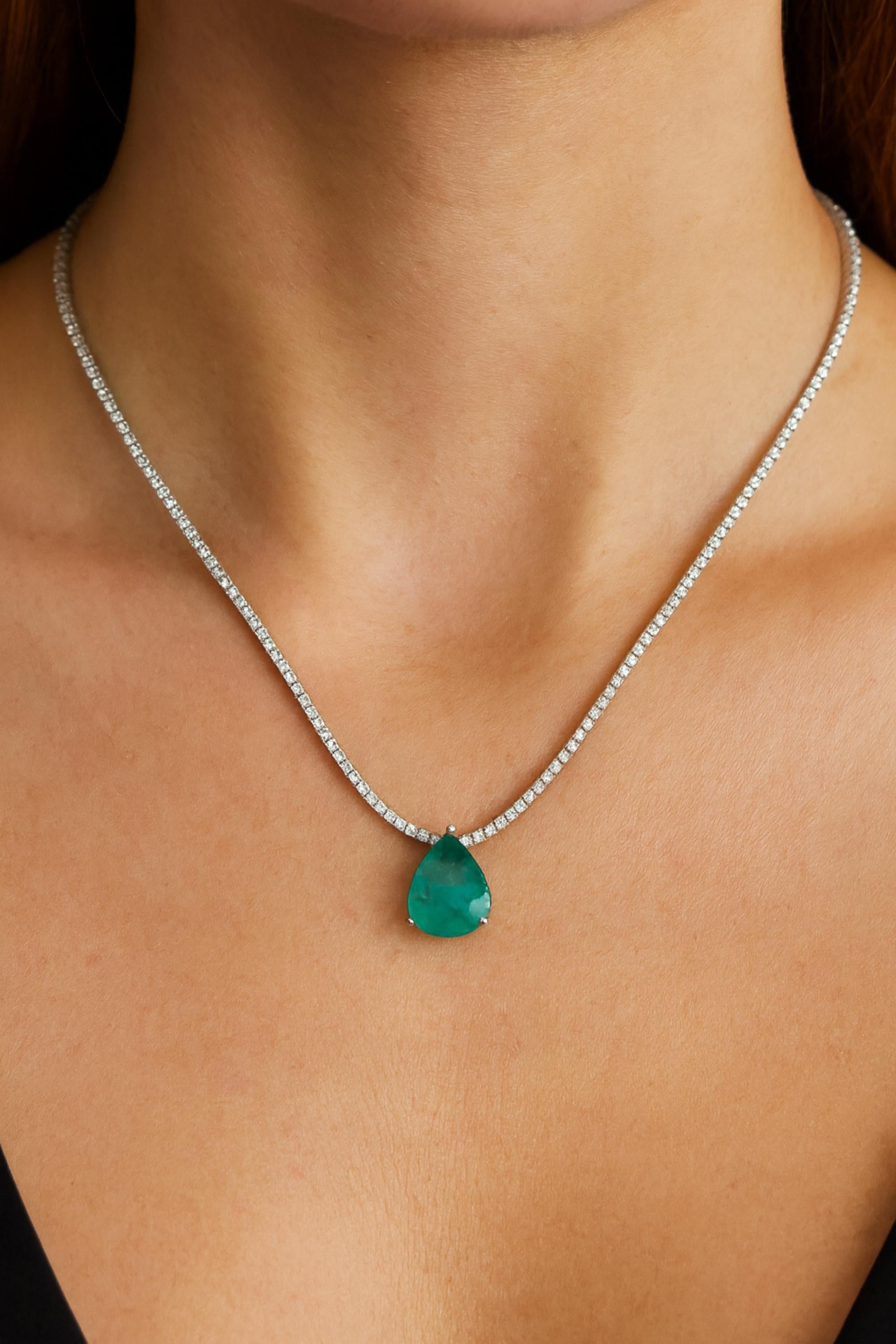 Collana con smeraldo dello Zambia in oro bianco 14 carati e catena di diamanti
Il design è caratterizzato da un pendente a forma di smeraldo a pera sospeso con grazia da una linea continua di diamanti tondi brillanti, che formano una classica catena