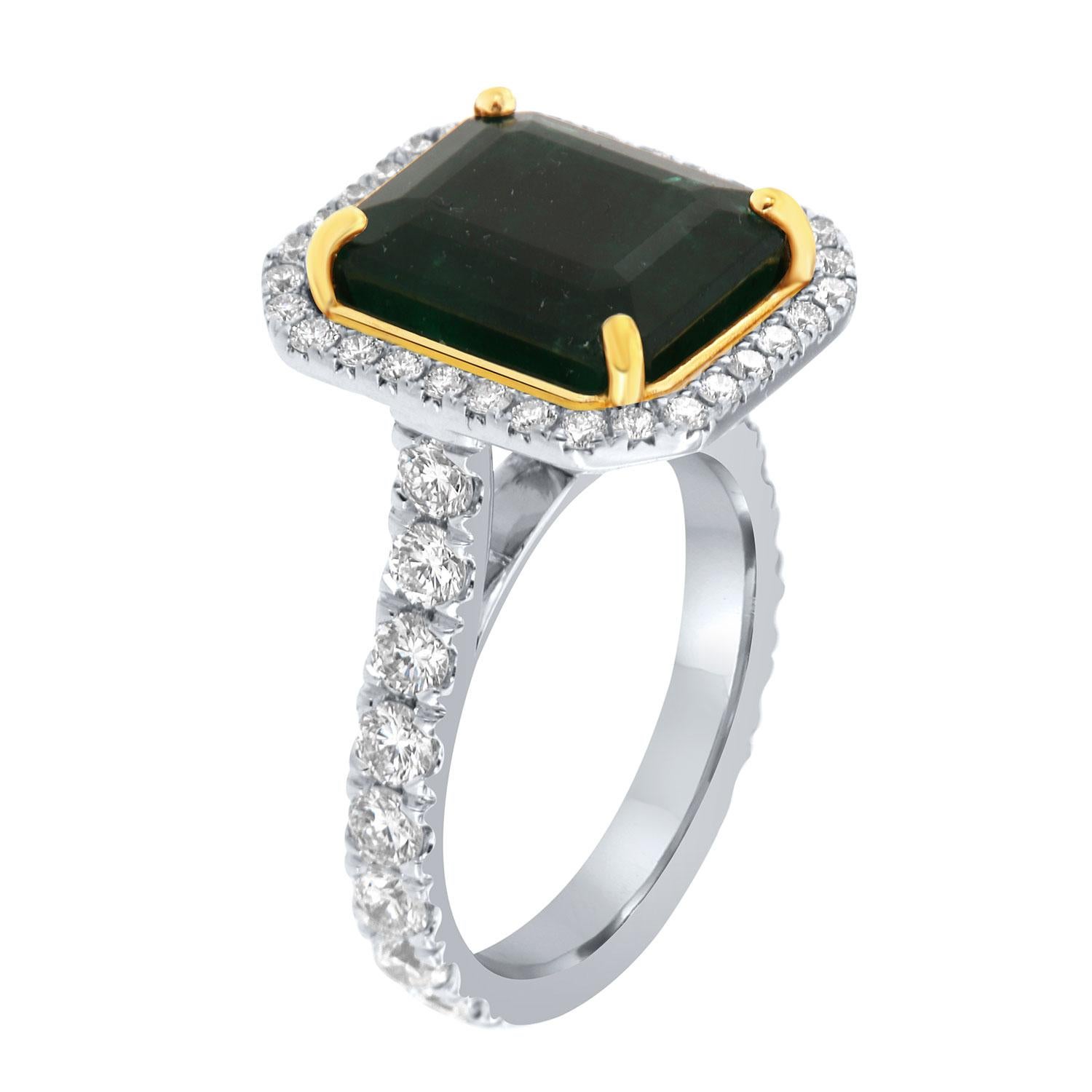 This 18k white and yellow gold ring features a 7.51 Carat Emerald cut Natural Green emerald from Zambia. It is encircled by a halo of brilliant round diamonds on a 3.3 mm wide band. The diamonds are Micro-Prong set on 75% of the band.  The diamond's