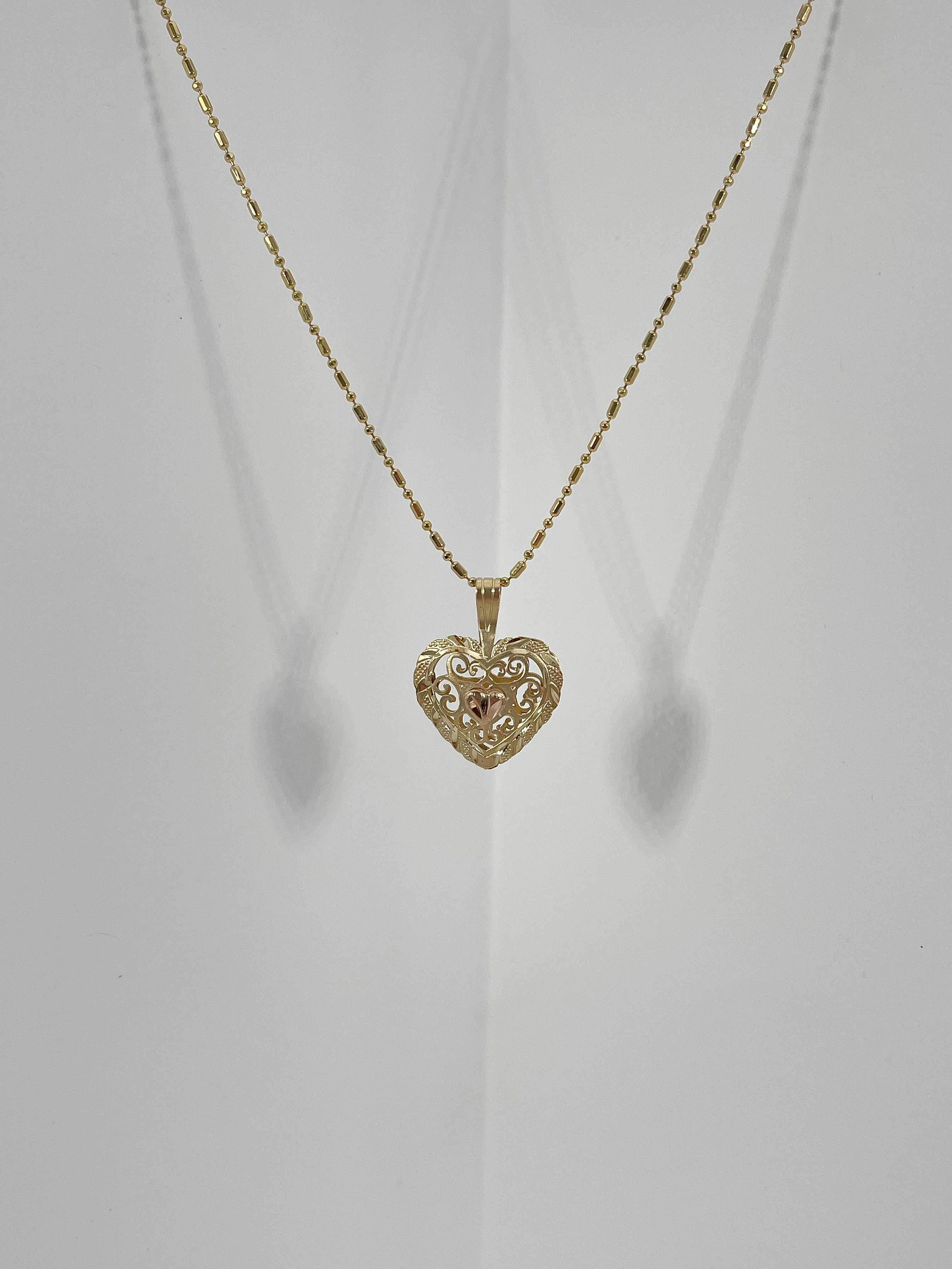14k yellow and rose gold filigree heart pendant necklace. The pendant comes on a 20 inch beaded chain, has a spring ring clasp to open and close, the pendant measures to be 16.5mm x 17.5mm, and has a total weight of 4.2 grams.