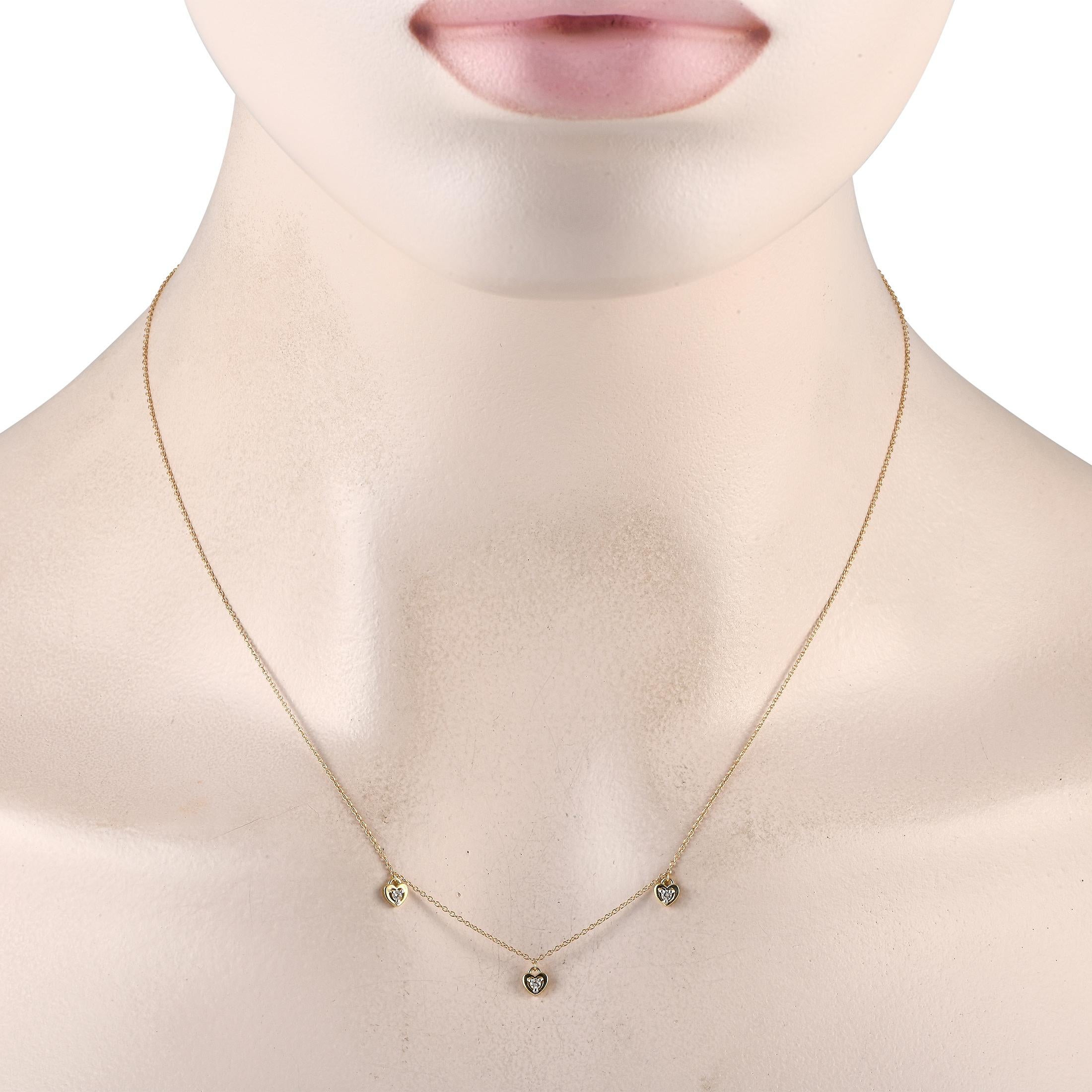 Simple, élégant et parfaitement discret, un trio de pendentifs en forme de cœur pend délicatement de ce collier en or jaune 14 carats à la chaîne délicate de 18. Des accents de diamant d'un poids total de 0,10 carat ajoutent un éclat subtil à cette