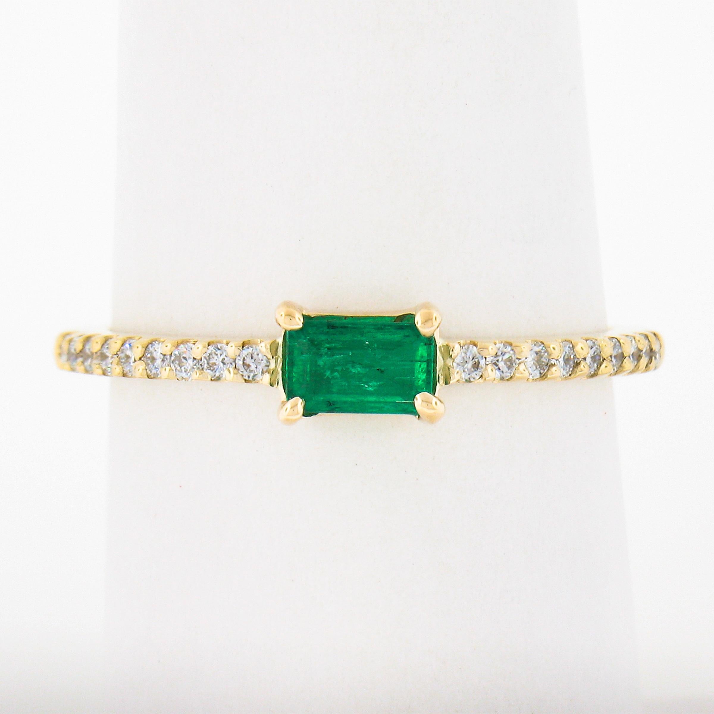 A simple yet gorgeous, emerald solitaire ring that is newly crafted from solid 14k yellow gold. The solitaire is elongated emerald cut with a nice vivid green color accented with 18 diamonds that are all set in prongs settings.