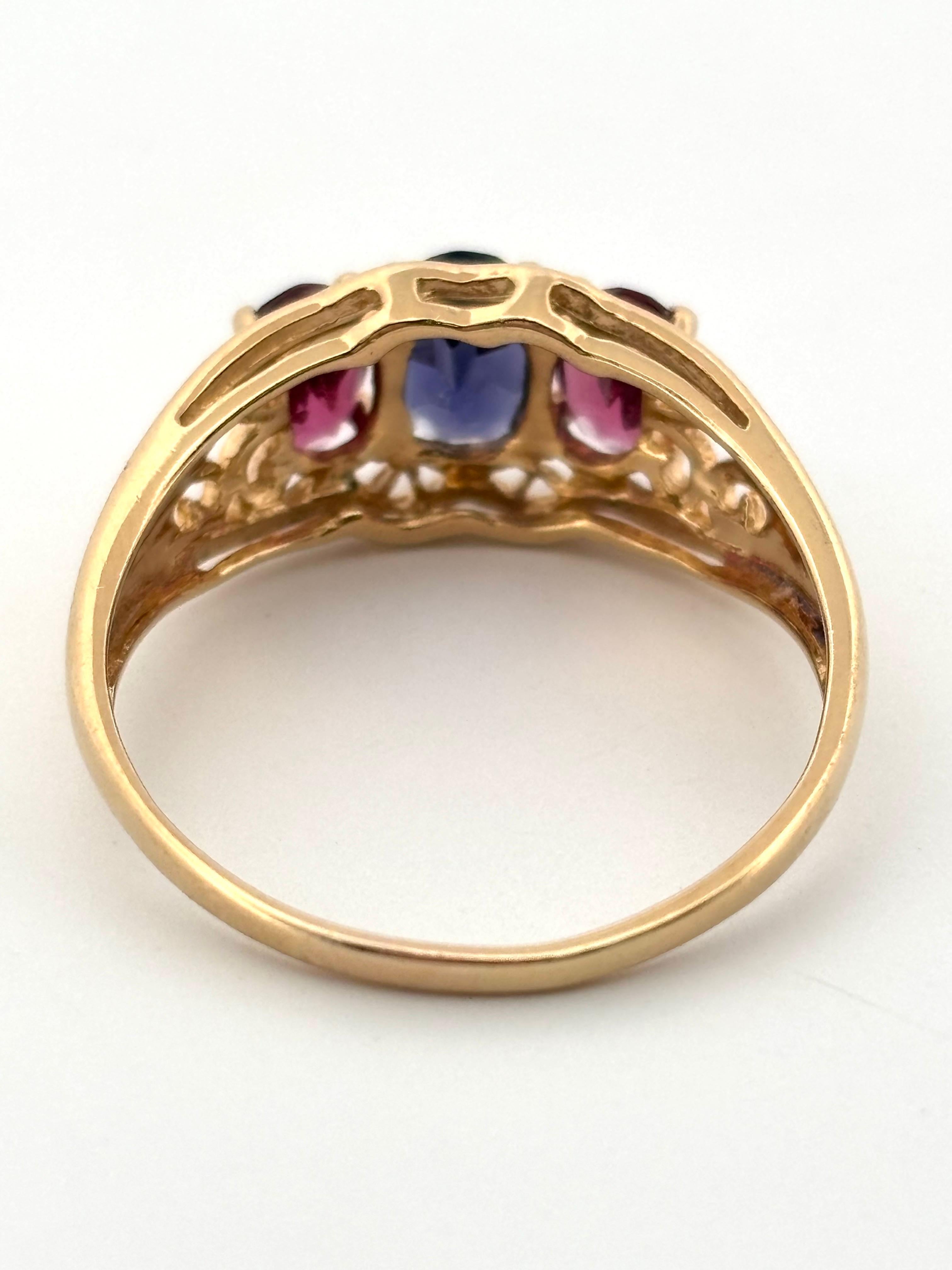 This elegant vintage three-stone ring is beautifully crafted in 14K yellow gold, showcasing a vibrant blend of color and timeless charm. At its center rests a 0.60 carat oval-cut iolite, displaying a deep violet-blue hue with enchanting brilliance.