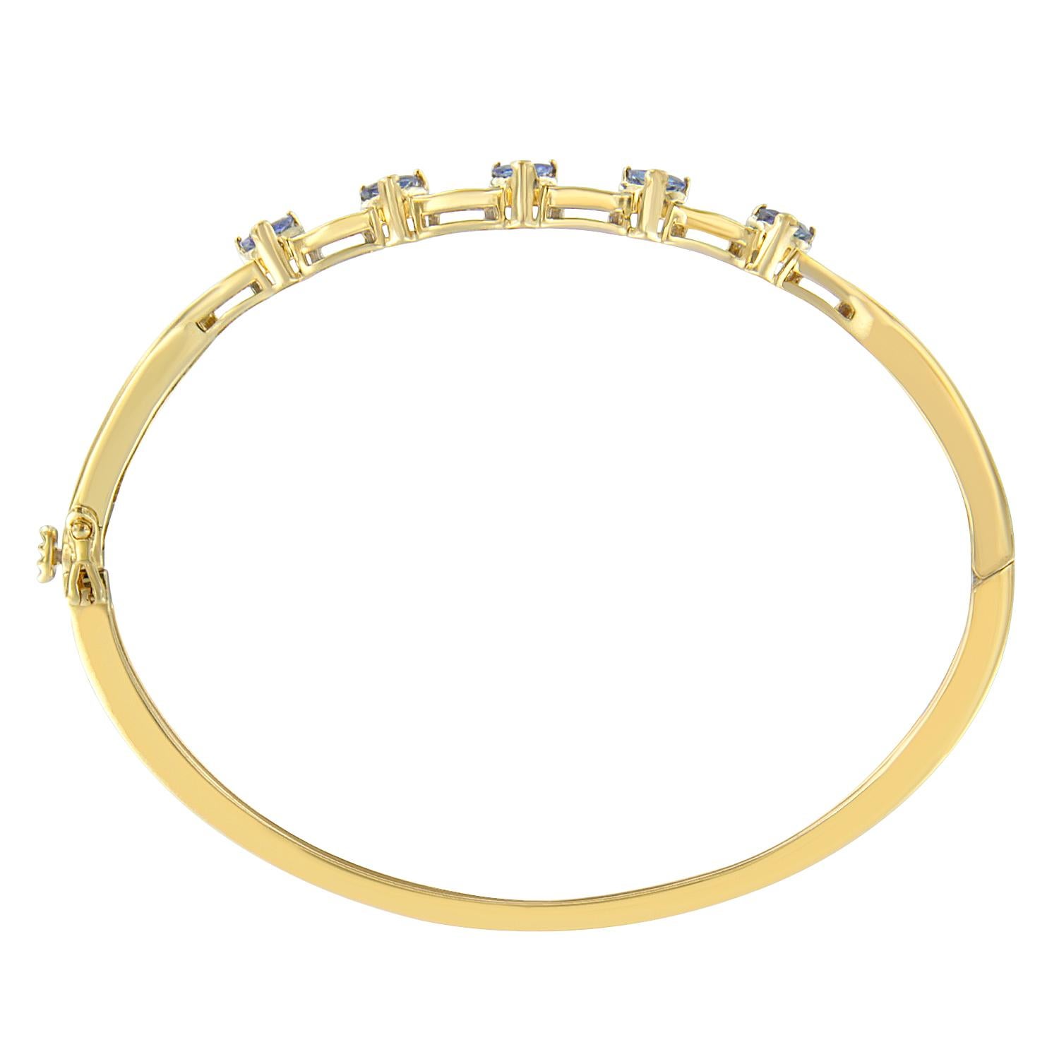 Make a bold statement with this stunning bangle, rendered in 14-karat yellow gold. The bangle sparkles brilliantly genuine tanzanite and baguette cut diamonds. Bracelet has 24 natural, baguette diamonds. Each stone weighs approximately 0.01 for a