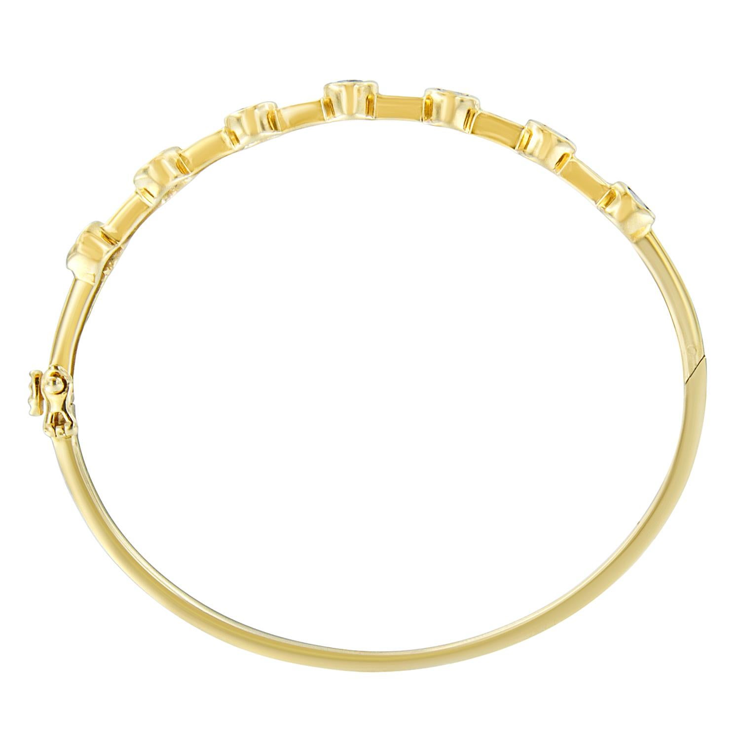 This elegant diamond and gemstone bangle invokes the classic feel of art deco. The 14k yellow gold bracelet features a series of oval tanzanite flanked by pairs of round diamonds. The rich royal blue gemstone is found in only one place on Earth.