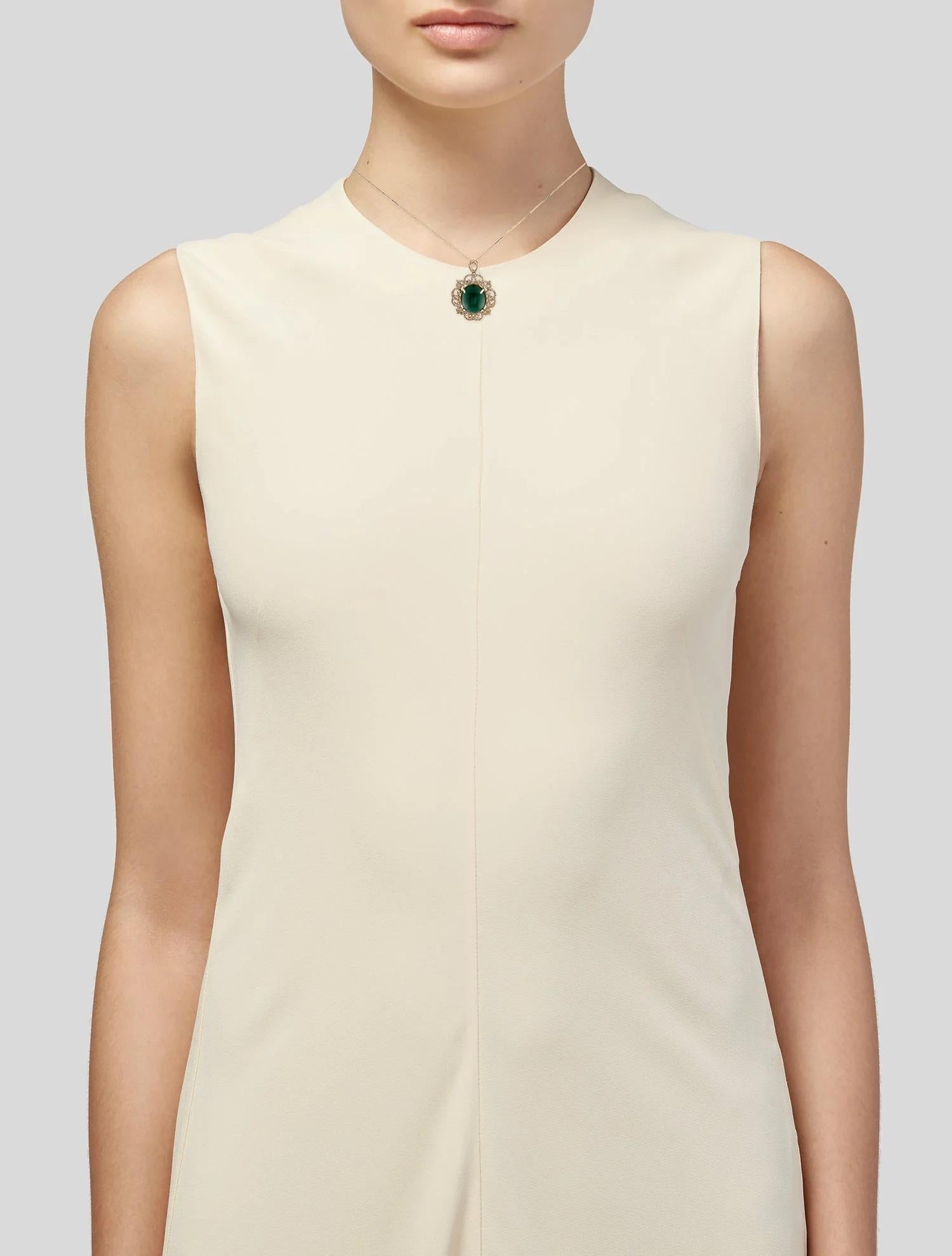 Rehaussez votre collection de bijoux avec ce collier pendentif opulent en or jaune 14 carats, orné d'une époustouflante émeraude cabochon ovale de 14,85 carats. La pierre centrale de couleur vert vif, avec sa saturation très légèrement grisâtre,