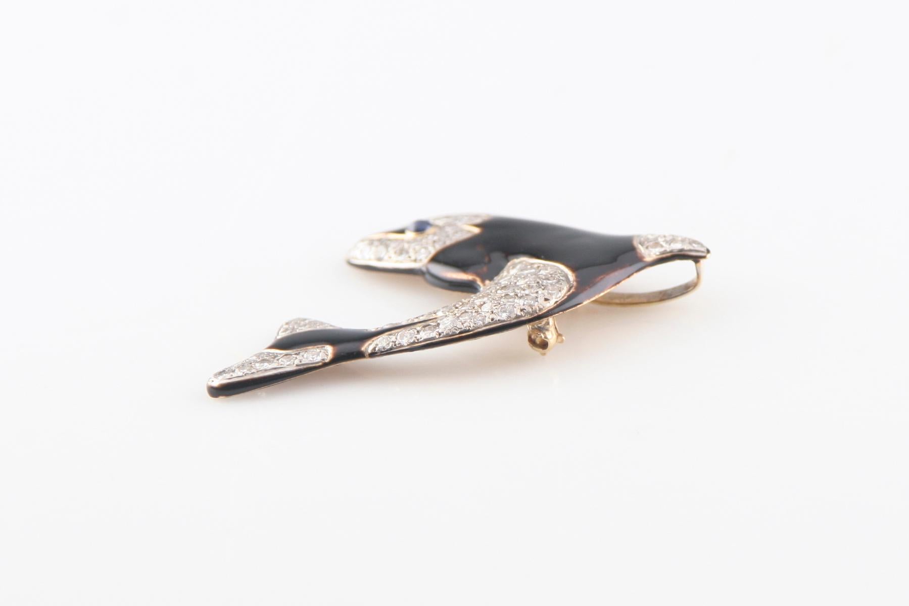 METAL: 14 KT Yellow Gold
FEATURES: The pendant/brooch features a  jumping killer whale. 
The body of the whale is  composed of black enamel and diamond set  sections accented with rhodium. 
The eye of the  whale is accented with a Blue