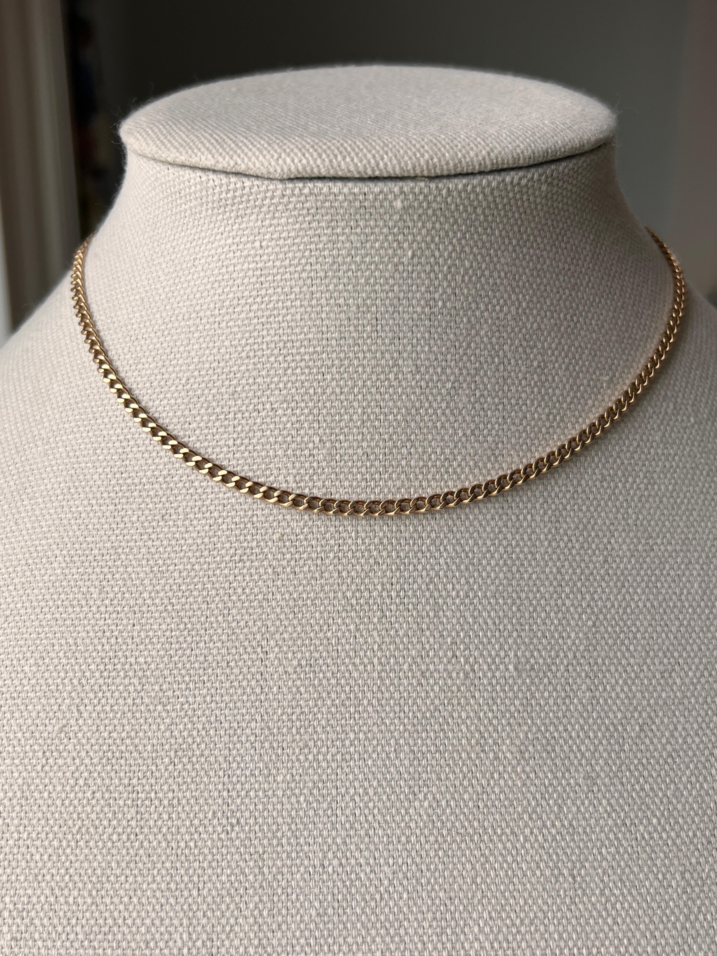 One 14 karat yellow gold watch chain dates to 1917, reflecting the refined craftsmanship of the early 20th century. Measuring 15 inches in length and weighing 10.51 grams, it features its original large spring ring clasp and a bold swivel clip, both