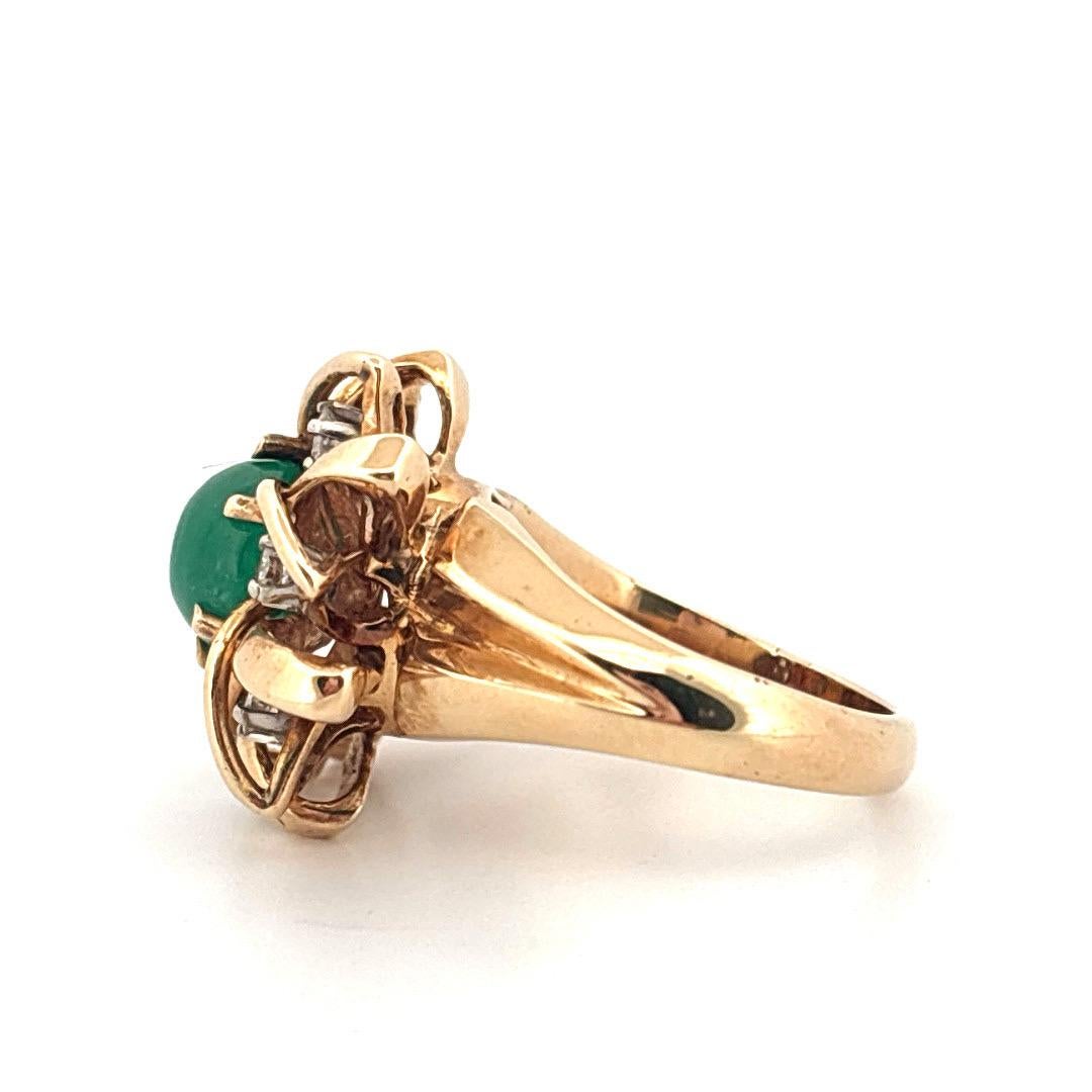 Questo squisito anello vintage è realizzato in ricco oro giallo 14k e presenta al centro un vibrante smeraldo cabochon da 1,65 carati. La tonalità verde intenso dello smeraldo è splendidamente completata da un'incastonatura dinamica e scultorea che