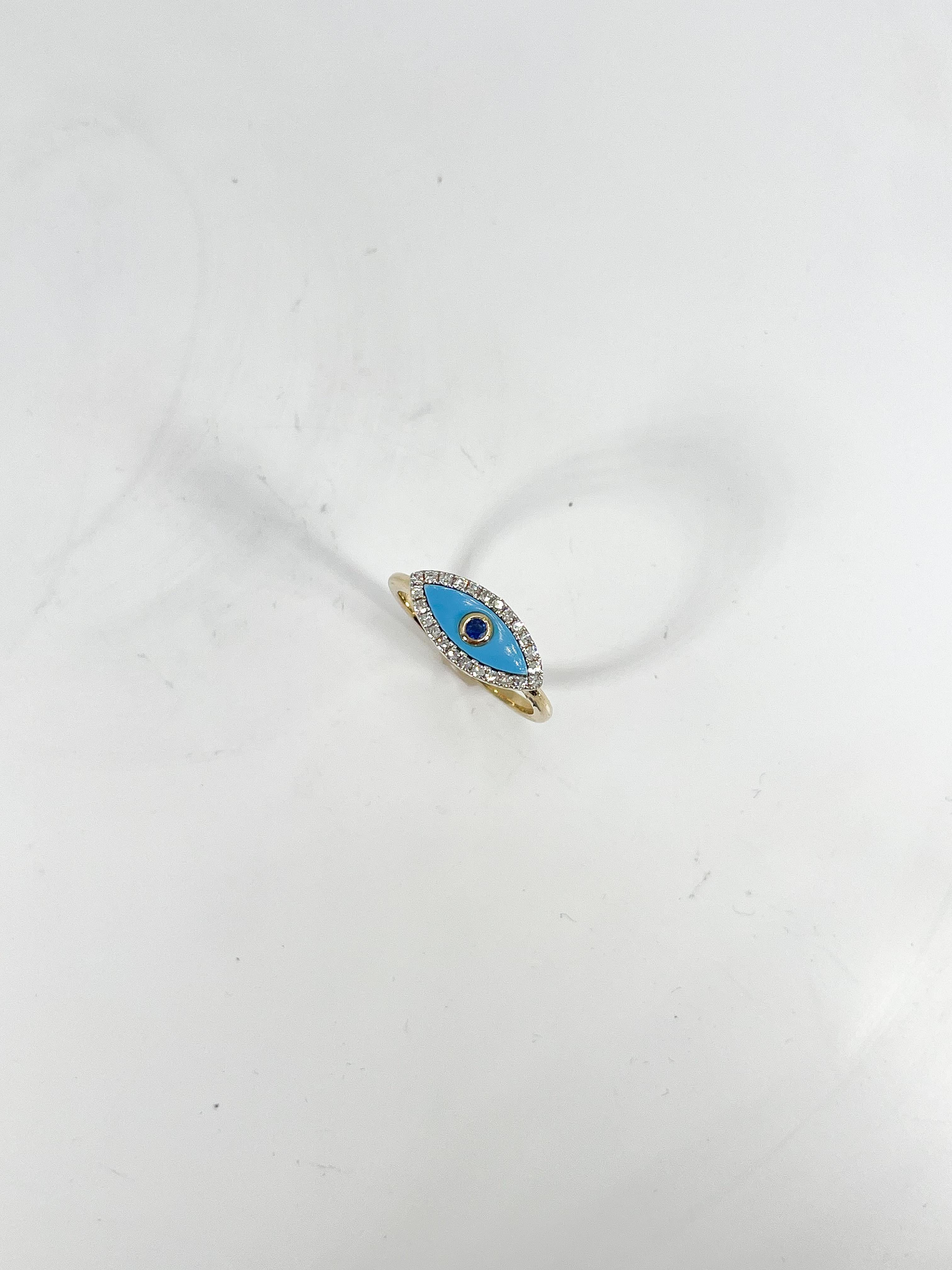 14k yellow gold .17 CTW diamond, .23 CTW turquoise, and .04 CTW sapphire evil eye ring. The width of the ring is 7.1 mm, measures to be a size 7, and has a weight of 2.7 grams. 