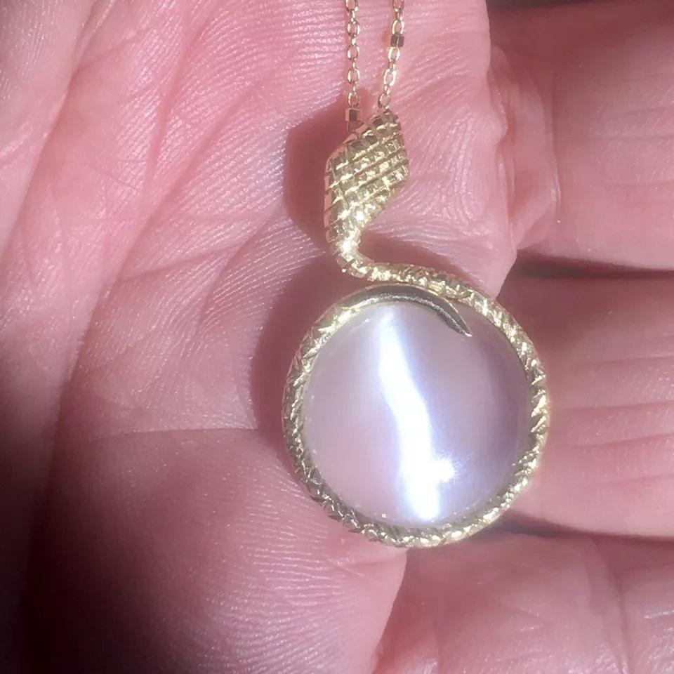 Ajoutez une touche d'élégance à votre tenue avec ce superbe collier en or jaune 14 carats de Nobel Gems, Inc. Le collier comporte un magnifique pendentif en pierre de lune cabochon ronde qui flotte au-dessus de la chaîne serpent. Le pendentif est