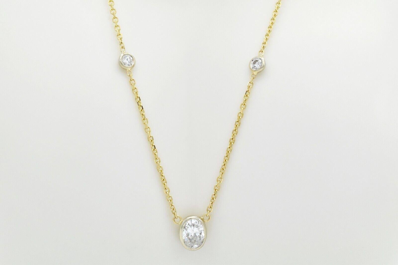 Cet élégant collier en or jaune 14k présente un design raffiné et minimaliste mis en valeur par cinq diamants sertis en chaton. En son centre, un brillant diamant ovale de 1,20 carat est enchâssé dans une lunette en or blanc pour un effet bicolore