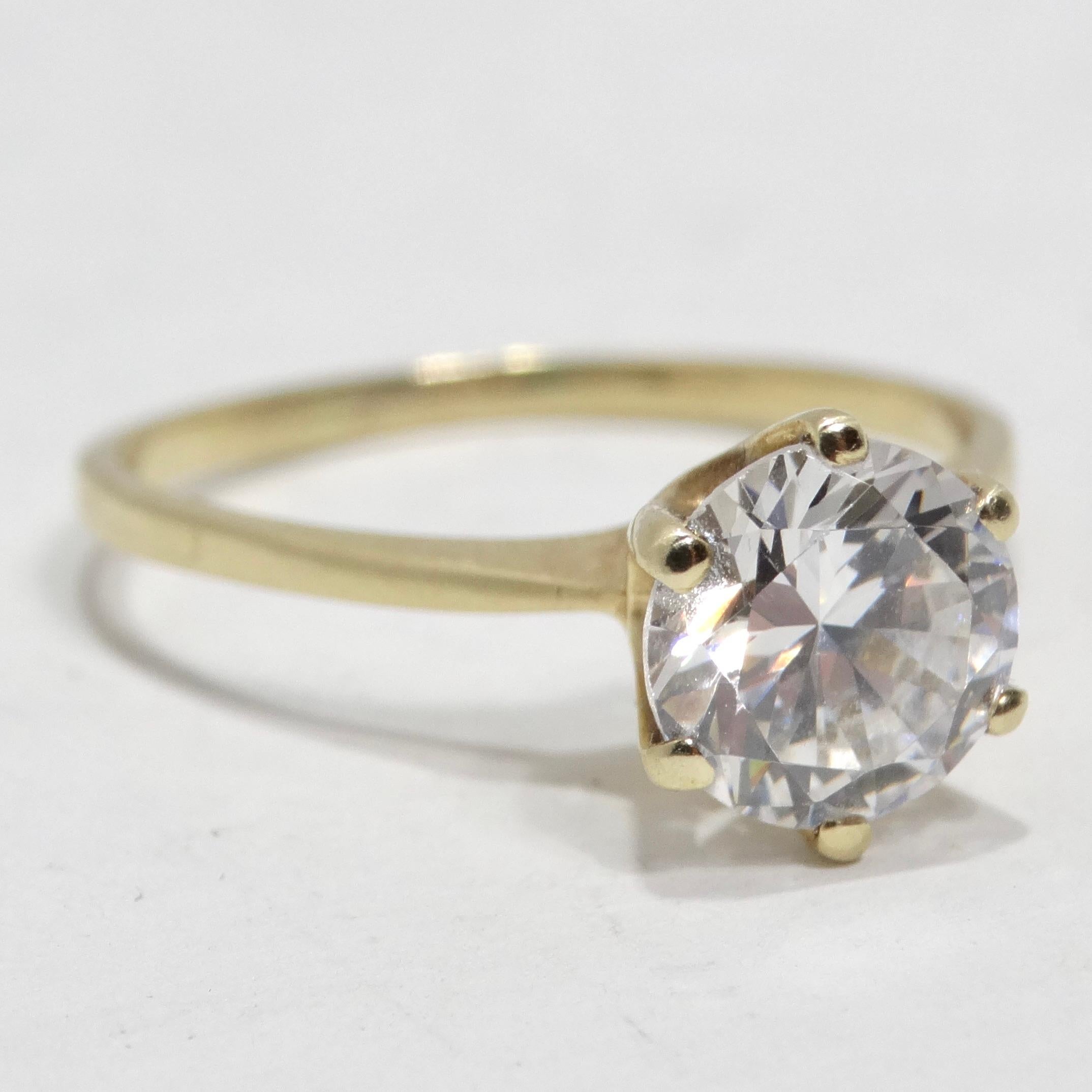 Introducing a ring that encapsulates the essence of timeless romance - the 14K Yellow Gold 1980s Cubic Zirconia Engagement Ring. This beautiful classic engagement ring boasts a subtle 14K yellow gold band that gracefully complements a stunning clear