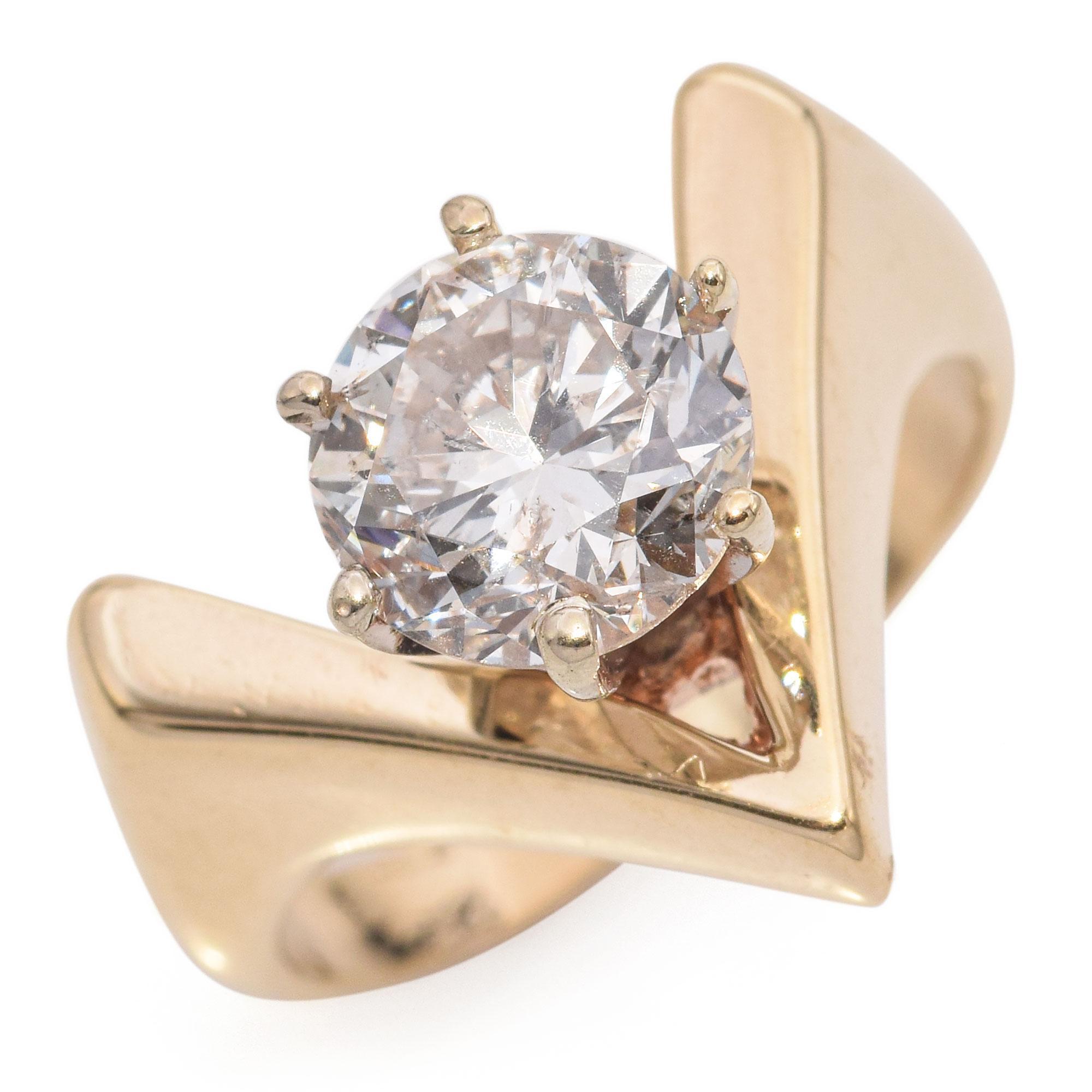 A striking engagement ring, this 14k gold piece features a stunning round cut diamond weighing 2.0 carats. The diamond displays a captivating white hue with an I color grade and I2 clarity, adding a unique character to the piece. The ring's design
