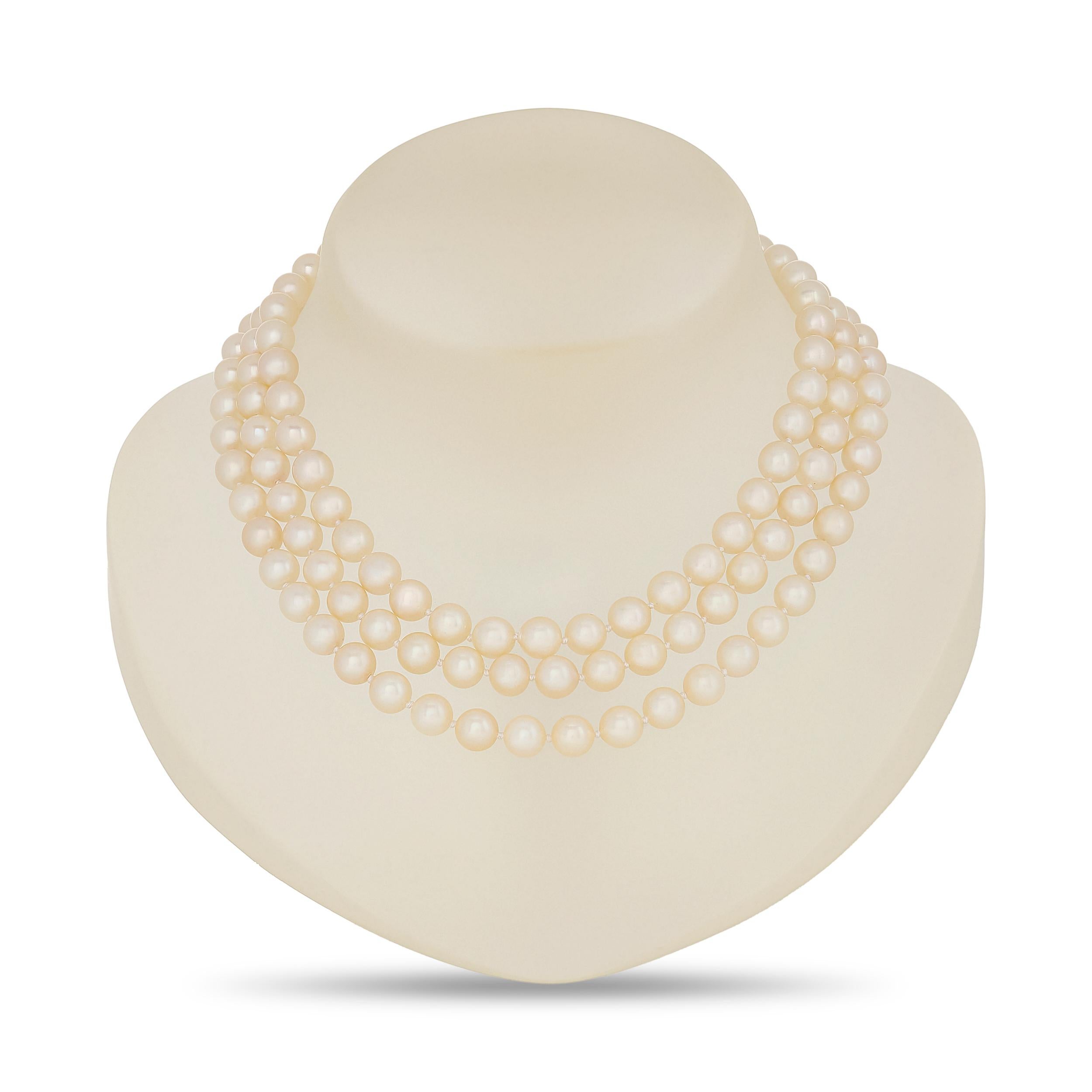 Questa collana di perle a tre fili, composta da lucenti perle bianche, è elegantemente chiusa da una vistosa fibbia in oro giallo 14 carati che presenta vibranti rubini, profondi zaffiri blu e scintillanti diamanti disposti in un motivo floreale, il