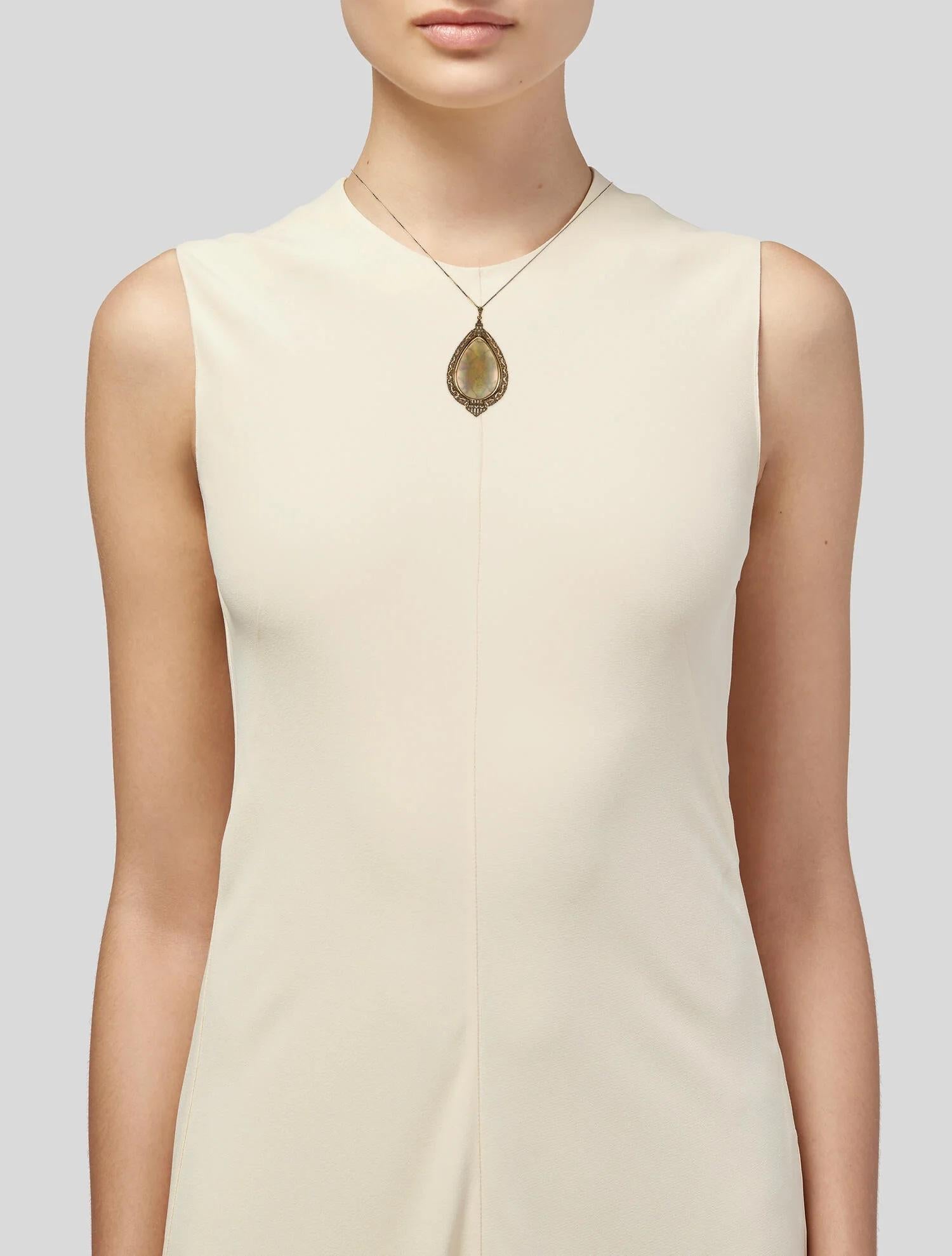 This striking 14K Yellow Gold Pendant Necklace features an impressive 32.17 carat pear-shaped opal cabochon, radiating with its colorless hue and captivating play-of-color. Accentuated by 10 near-colorless round brilliant diamonds totaling 0.66
