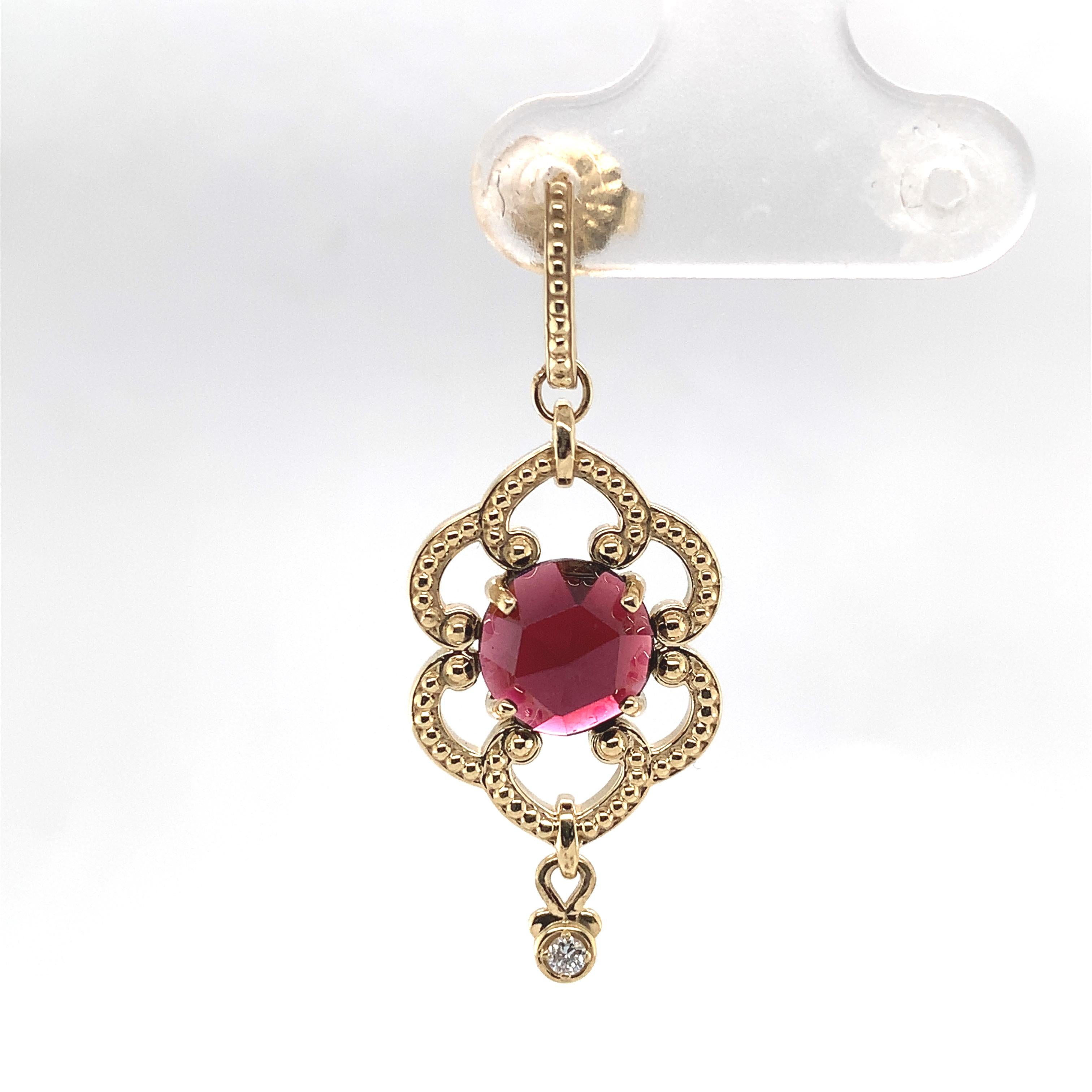 A pair of 14K yellow gold earrings featuring a pair of round rose cut garnets weighing 5.12 carats total. The red garnets measure 7mm. Beautiful scroll work and a tiny round diamond dangle accent measuring about 1.5mm. The earrings measure 1 1/2