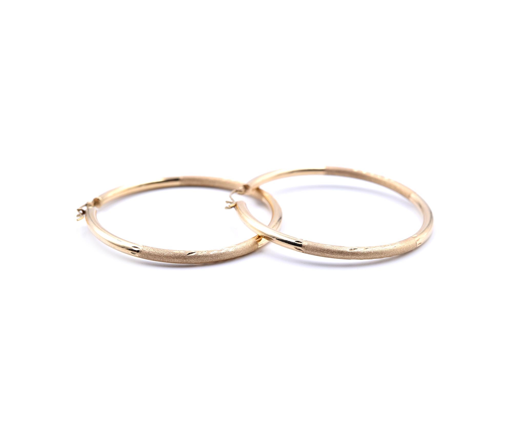 Designer: custom design
Material: 14k yellow gold  
Dimensions: earrings measure 50mm in diameter and are 3mm wide
Fastenings: post with saddle backs
Weight: 4.07 grams
